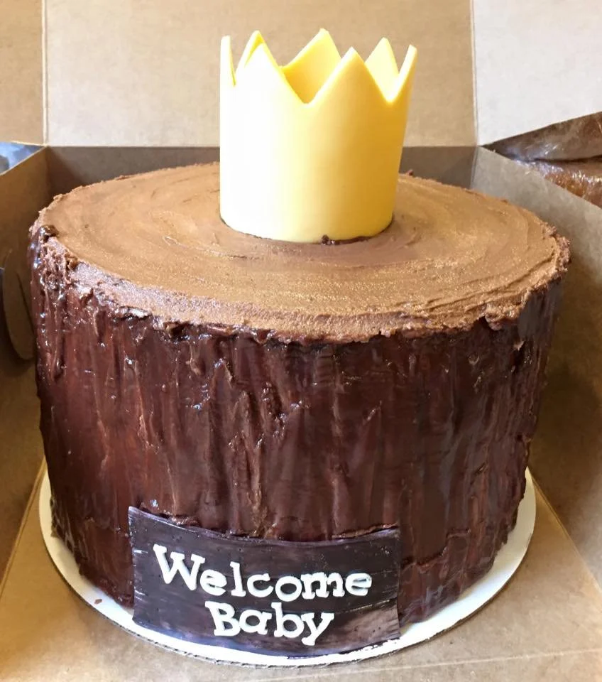 Rustic tree stump cake topped with crown for woodland themed celebration