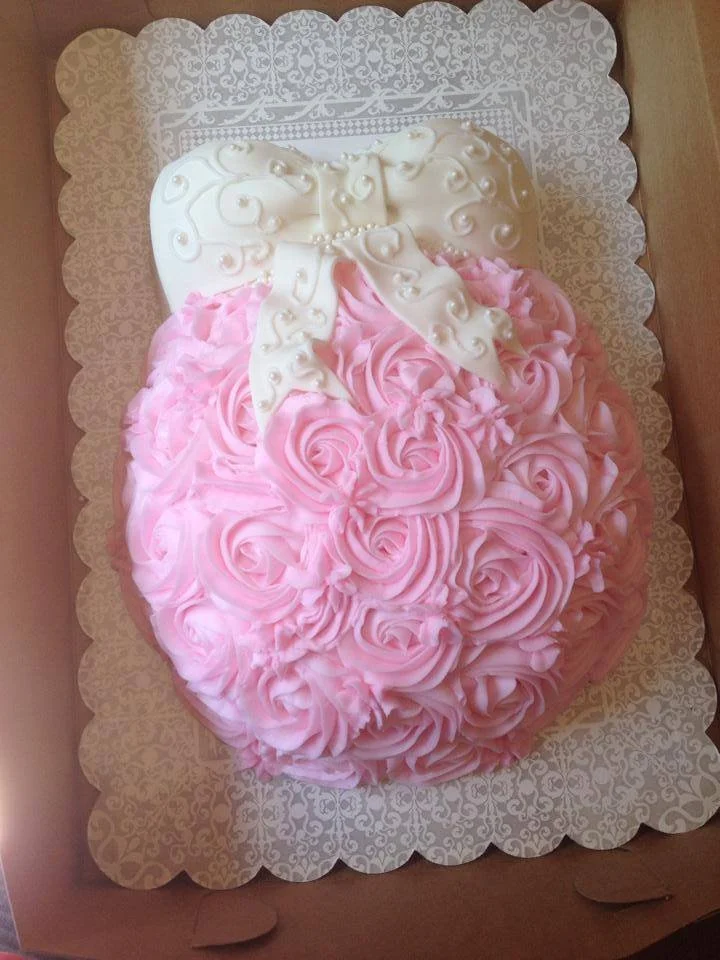 Sculpted pregnant belly cake with fondant bow and buttercream rosettes for baby shower