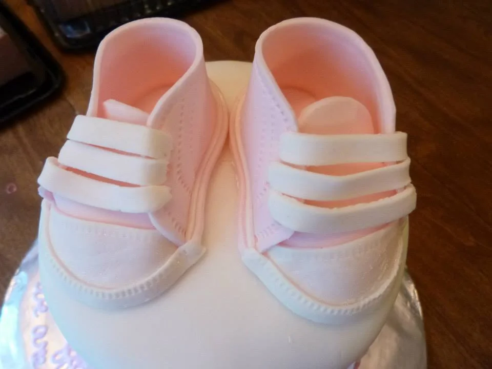Pair of sculpted baby sneaker cakes inspired by classic canvas shoes