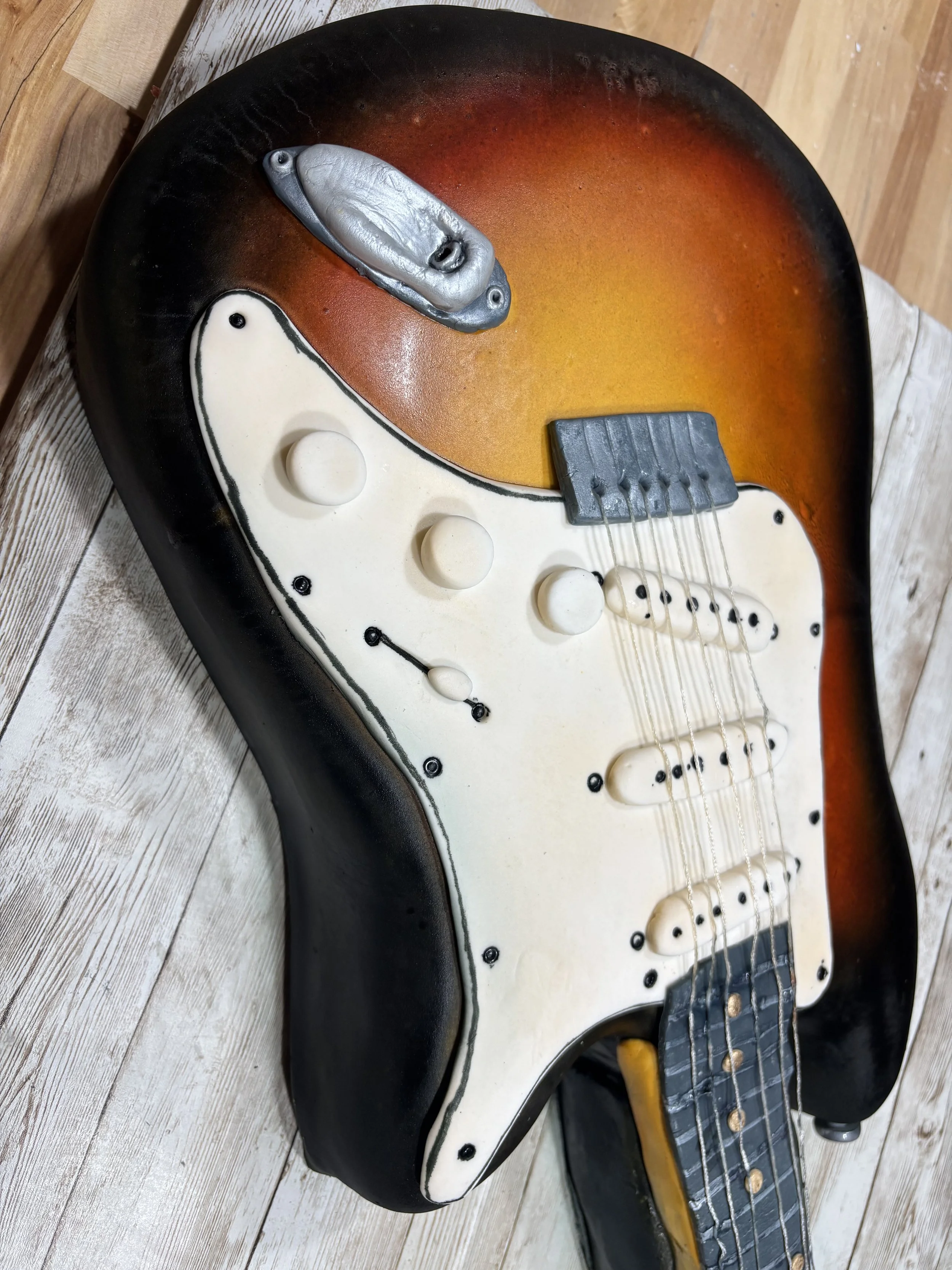 Detailed close-up of custom electric guitar cake with edible strings and hand-painted shading.