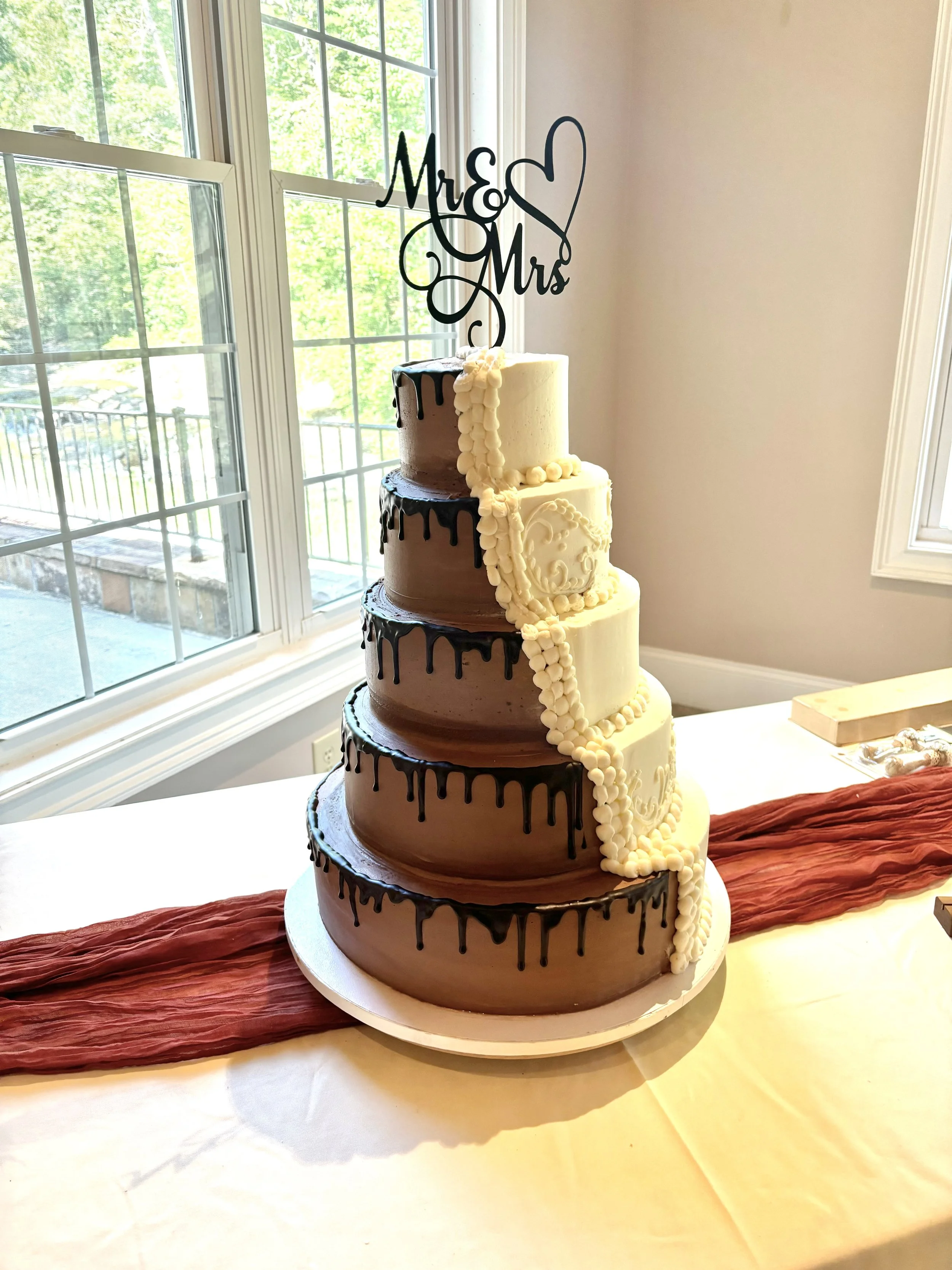 Five tiered wedding cake at Toccoa Falls, half chocolate, chocolate buttercream with ganache drip, half vanilla, vanilla buttercream with scrollwork