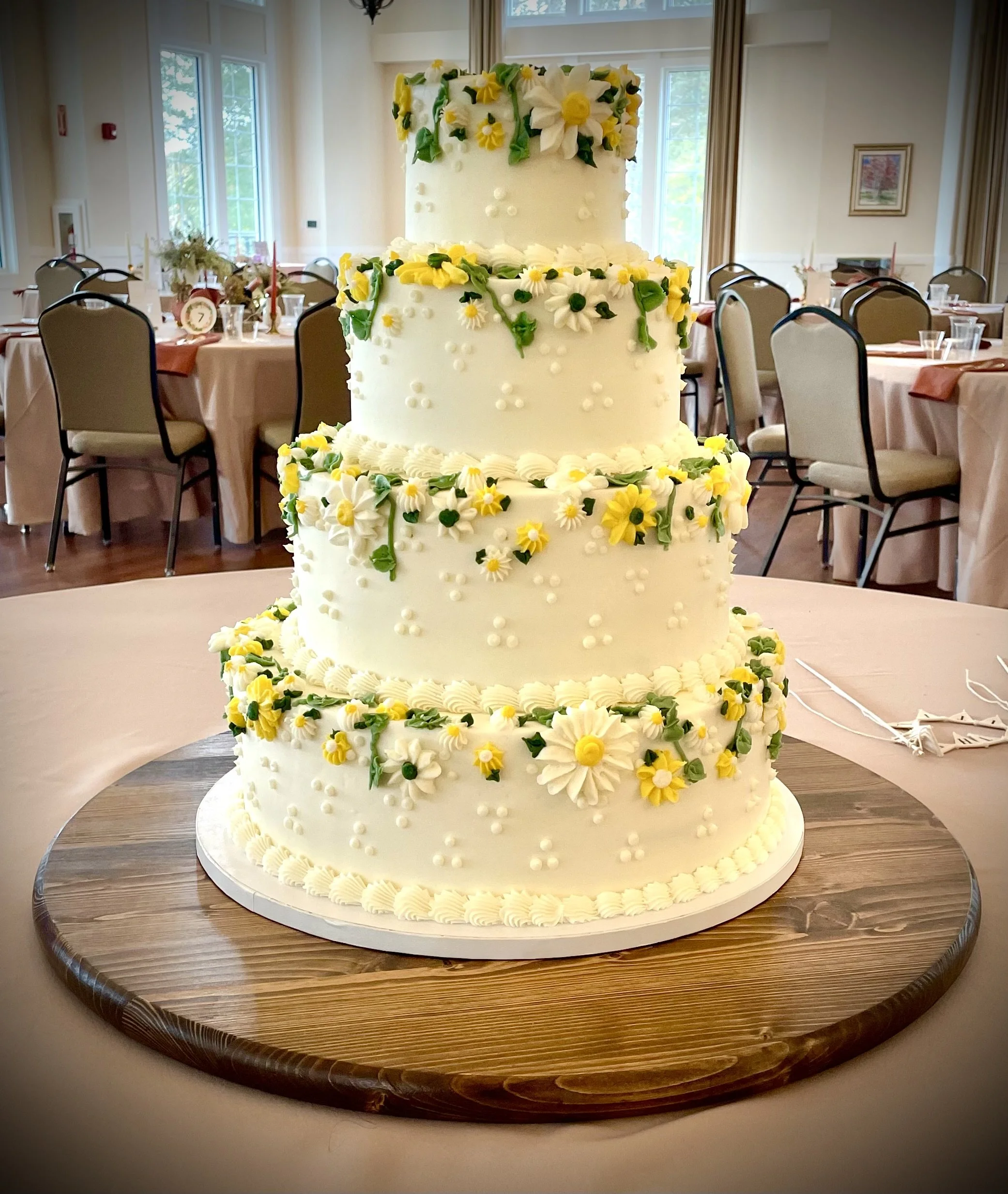 Four tiered buttercream wedding cake with yellow and white piped flowers.jpeg