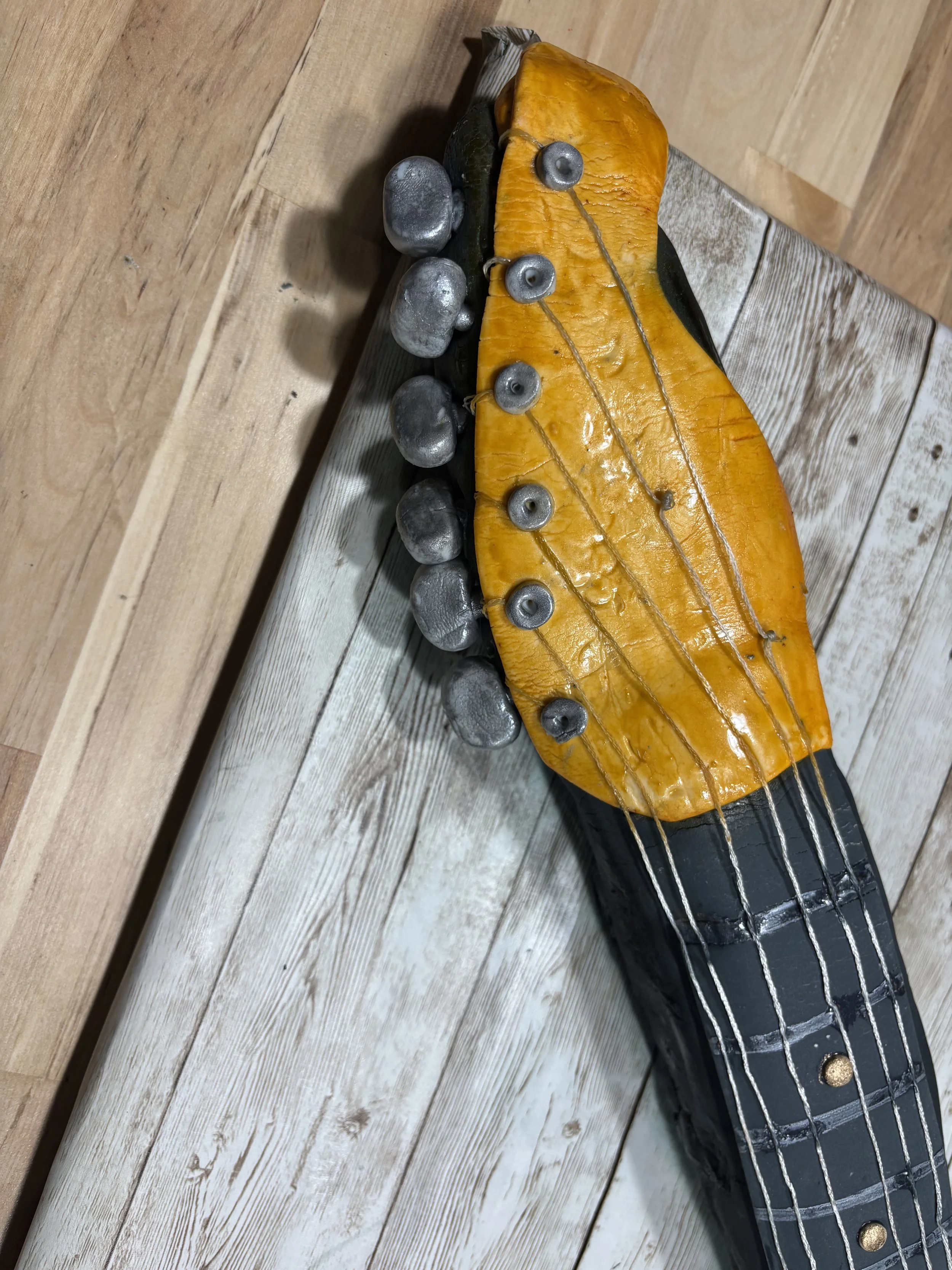 Close-up view of a realistic electric guitar cake by Artful Cakery by Julie, showcasing hand-painted sunburst colors, edible knobs, strings, and textured details that mimic an authentic vintage guitar. Custom sculpted cake for weddings, groom’s cakes
