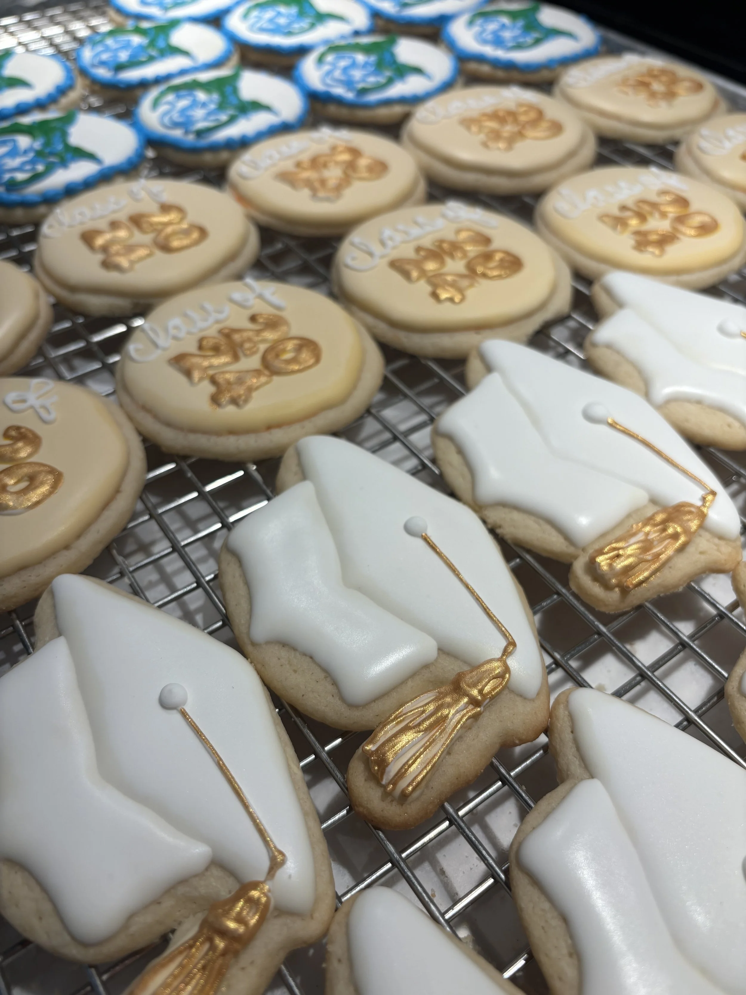 Cookies decorated with graduation themes, including diplomas and graduation caps, on a cooling rack.