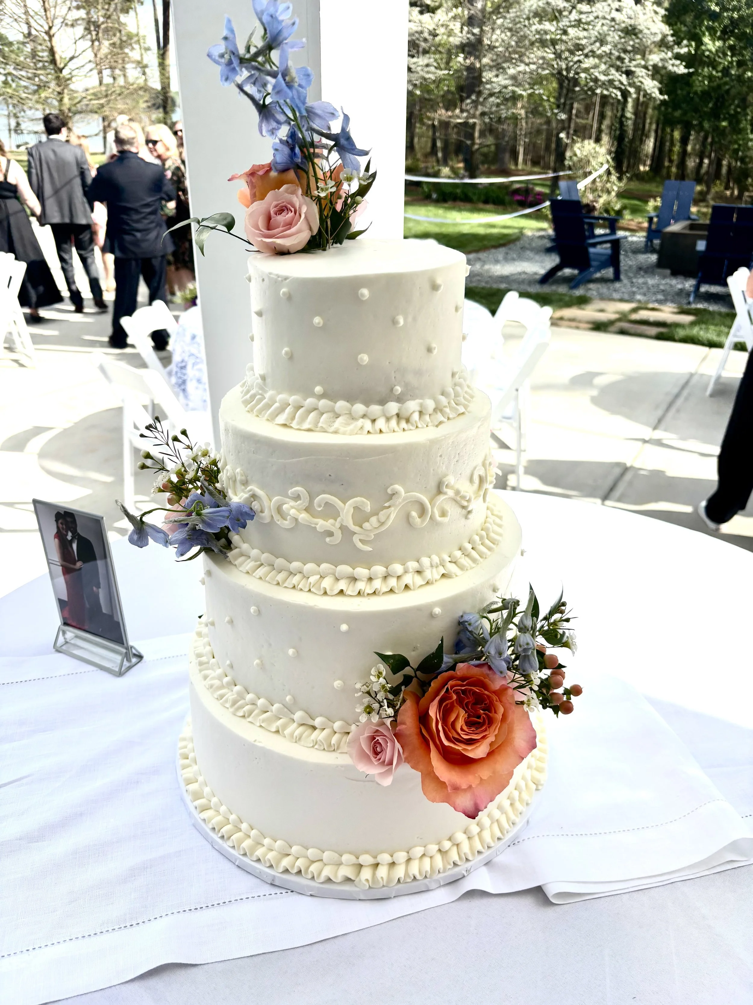 Four tiered buttercream wedding cake with subtle designs, fresh and colorful flower accents at a wedding in Cumming, Georgia on Lake Lanier