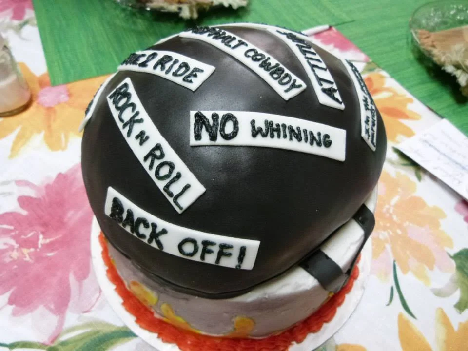 Sculpted motorcycle helmet cake with custom decals and sayings
