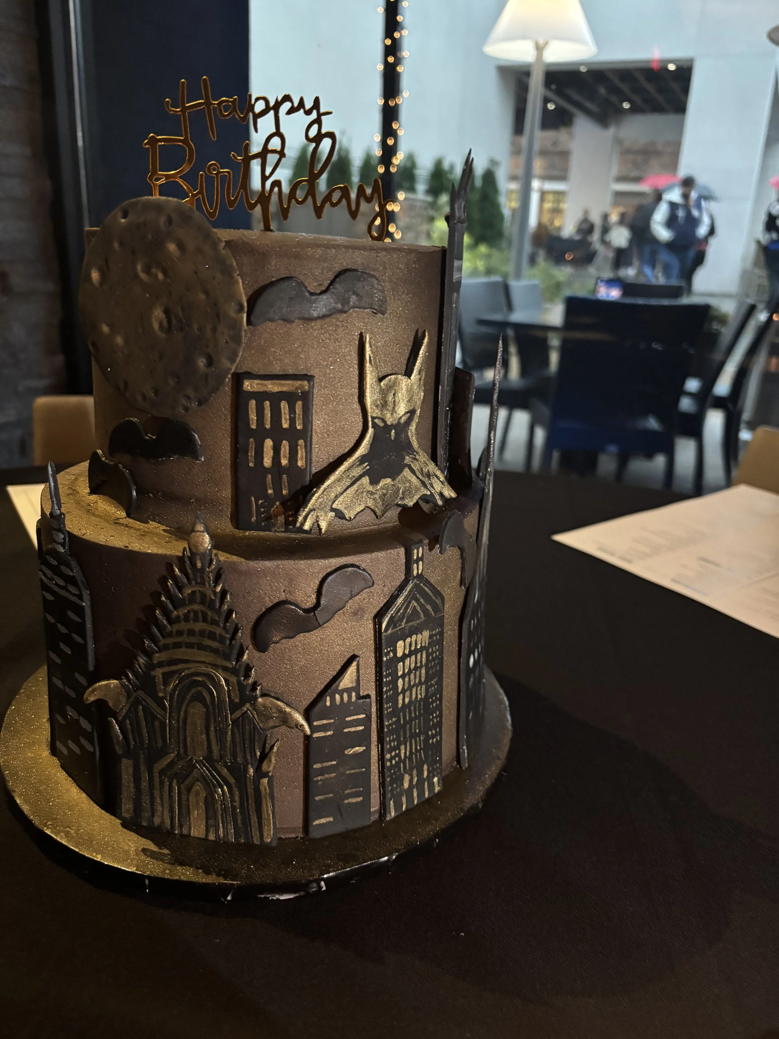 Batman inspired Gotham City cake with dramatic black and gold design.