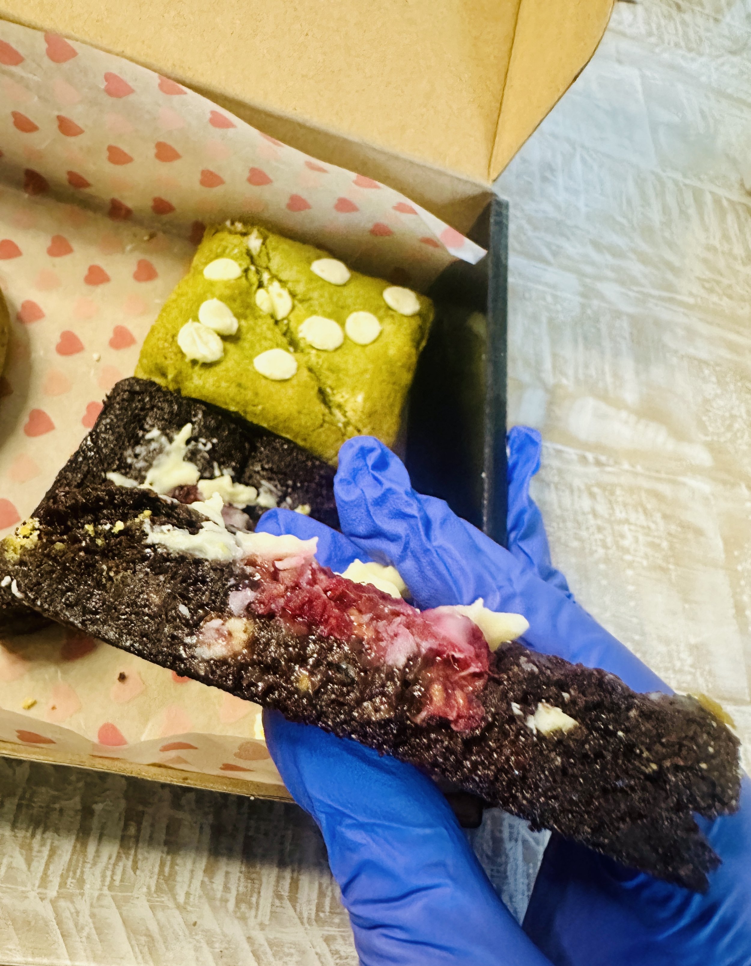Cross-section of raspberry white chocolate brownie being held showing dense fudgy texture with raspberry and white chocolate pieces