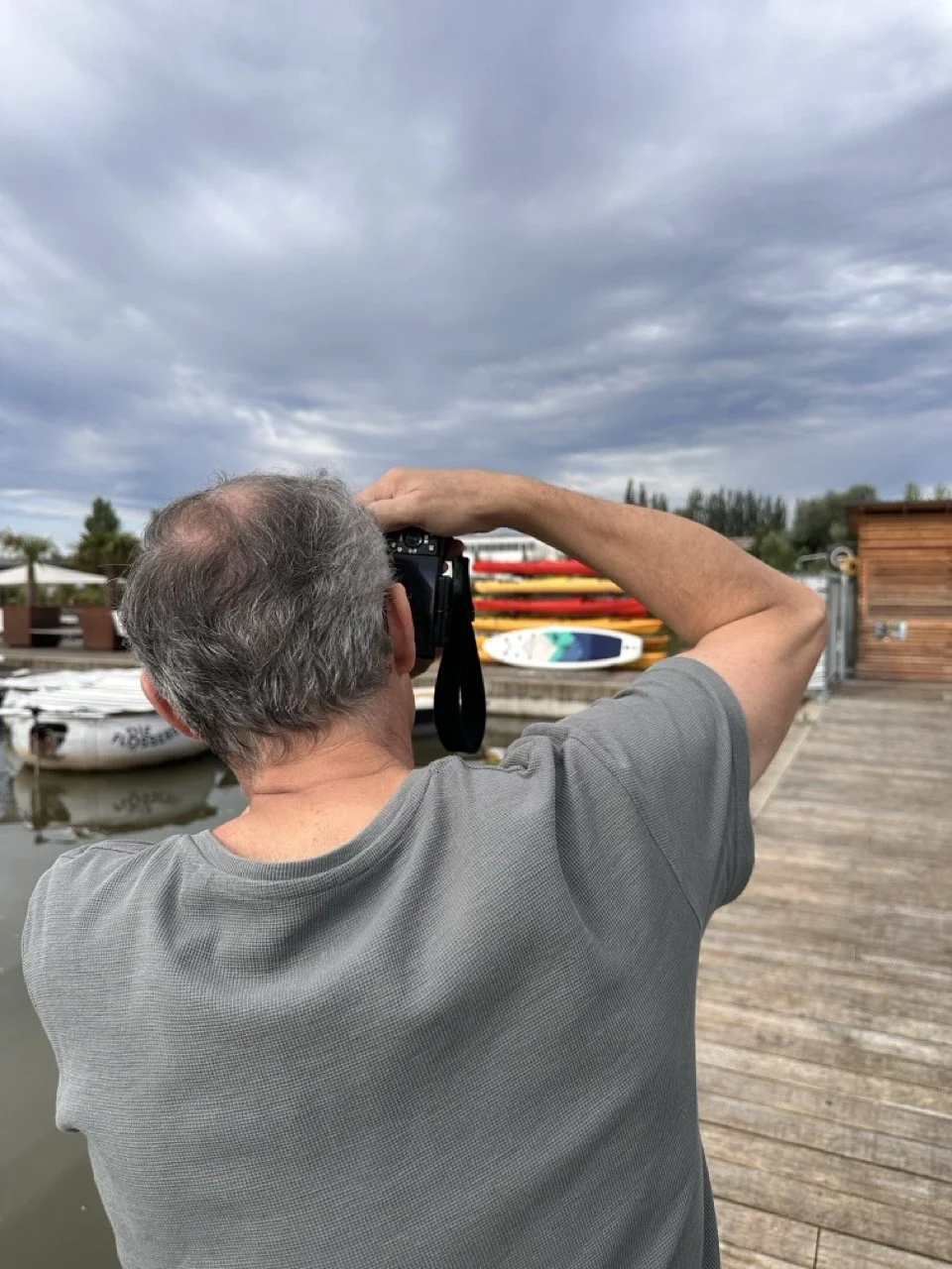 Mann fotografiert Boote am Wasserläufer bei bewölktem Himmel.