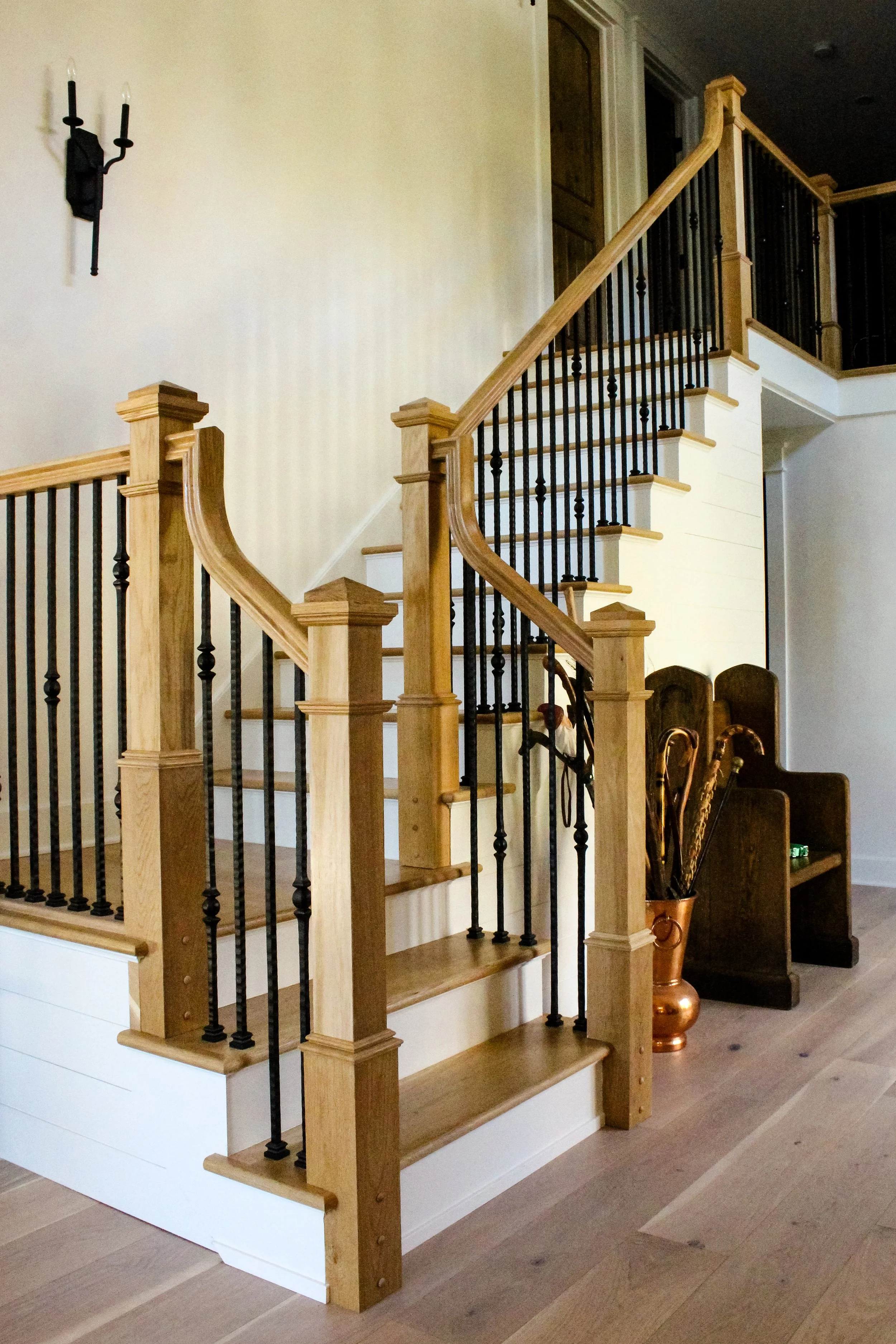 White interior staircase with wood treads and black balusters designed and manufactured by Empire Stairworks.