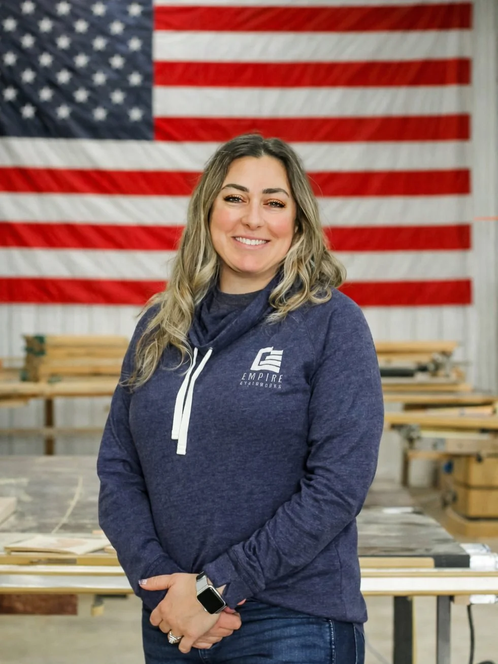 Empire Stairworks team members standing in the workshop in front of an American flag, representing local stair manufacturing