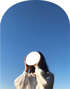 Person holding a white circular object in front of their face under a clear blue sky.