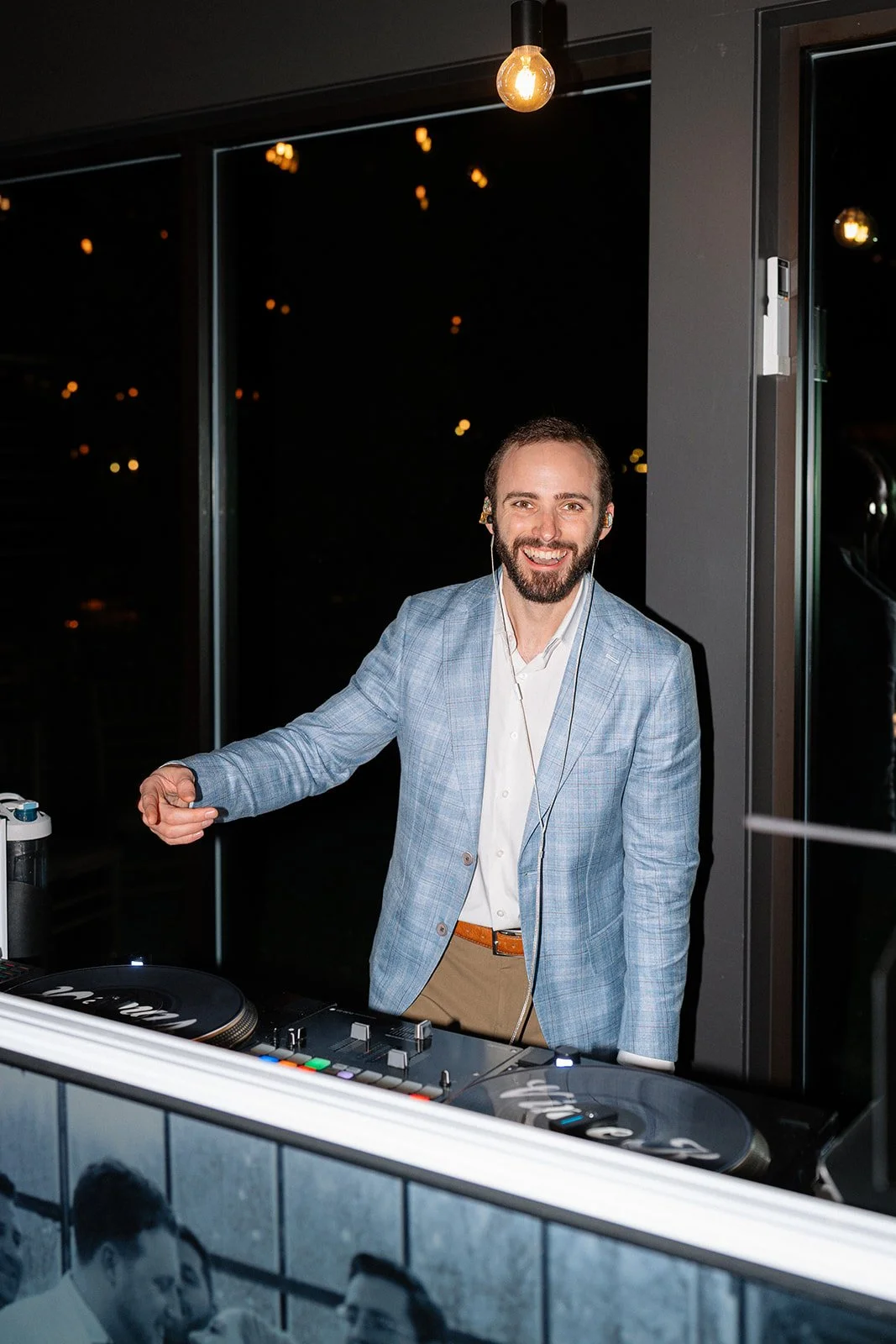 Vince Kendjorsky standing behind a DJ booth with turntables at night.