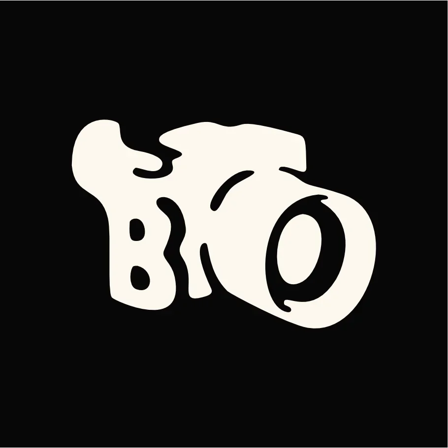 A stylized black and white logo of a Camera with bold, abstract shape.