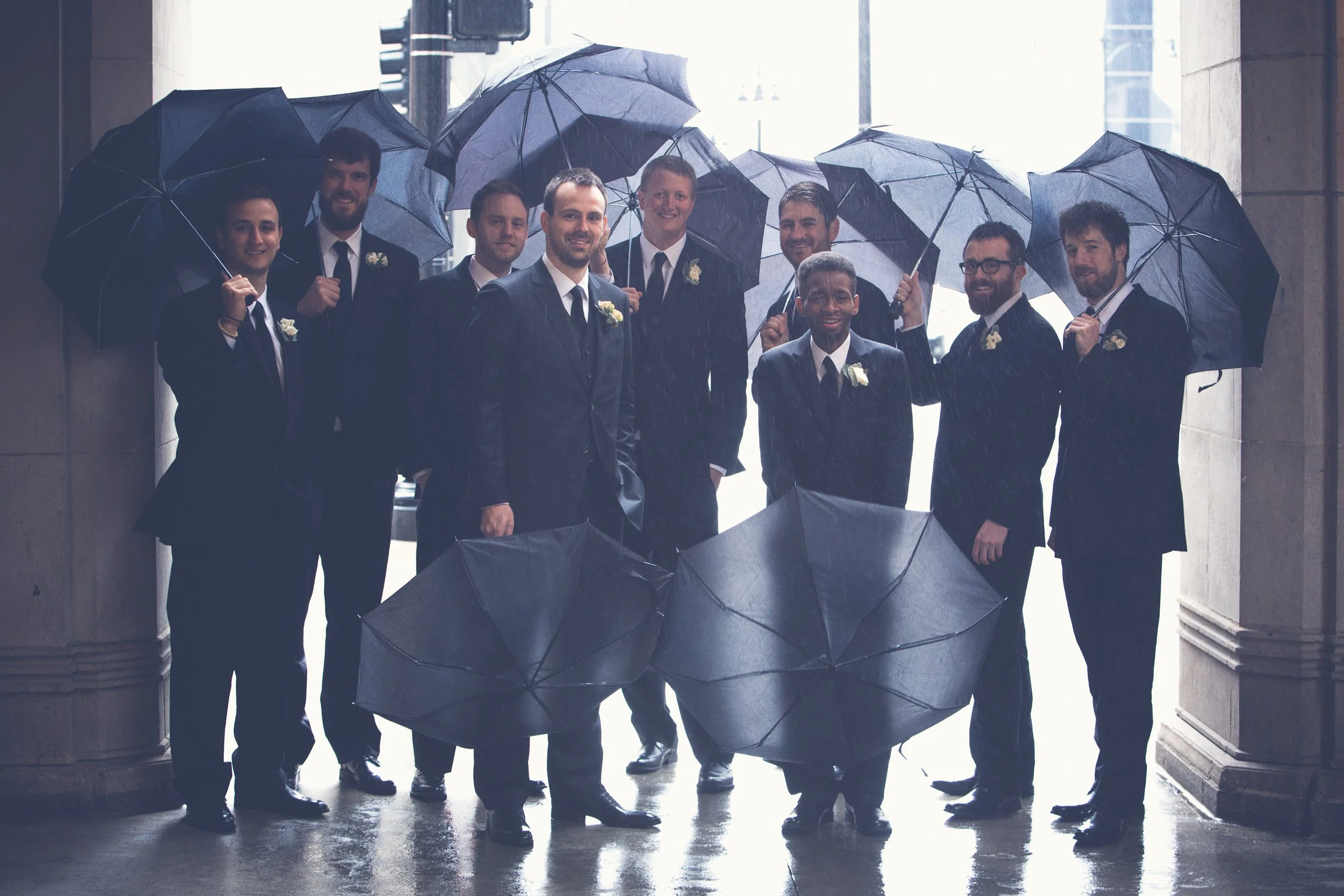 groom with groomsmen with umbrellas Lyric Opera House Chicago Wedding photographer near me