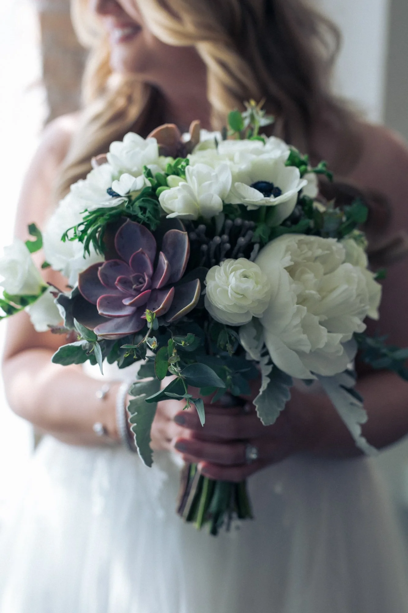 Bride holding a bouquet with white flowers and succulents.