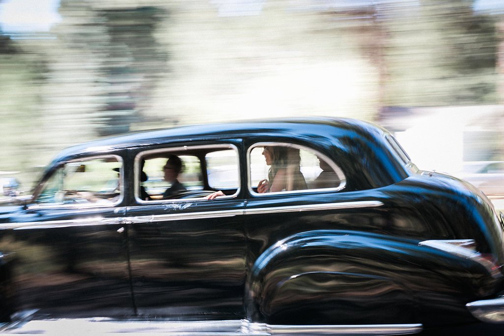 Vintage black car with passengers driving in motion blur