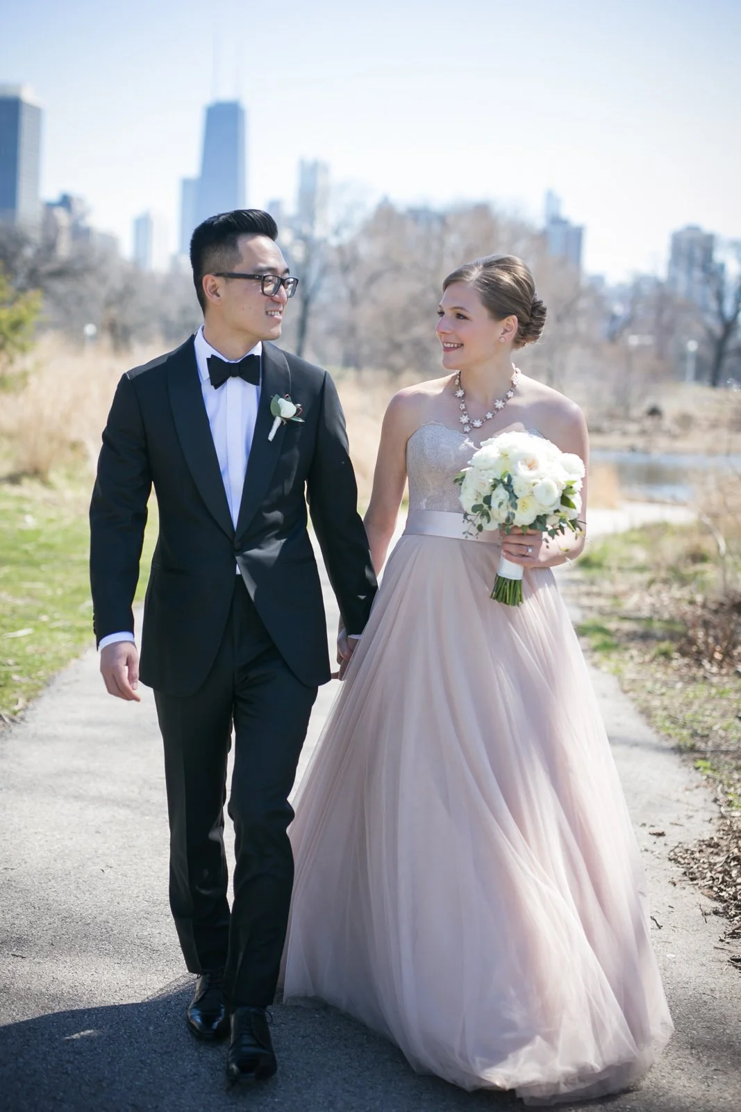 groom walking with bride with bouquet chicago lincoln park pond wedding photography near me 