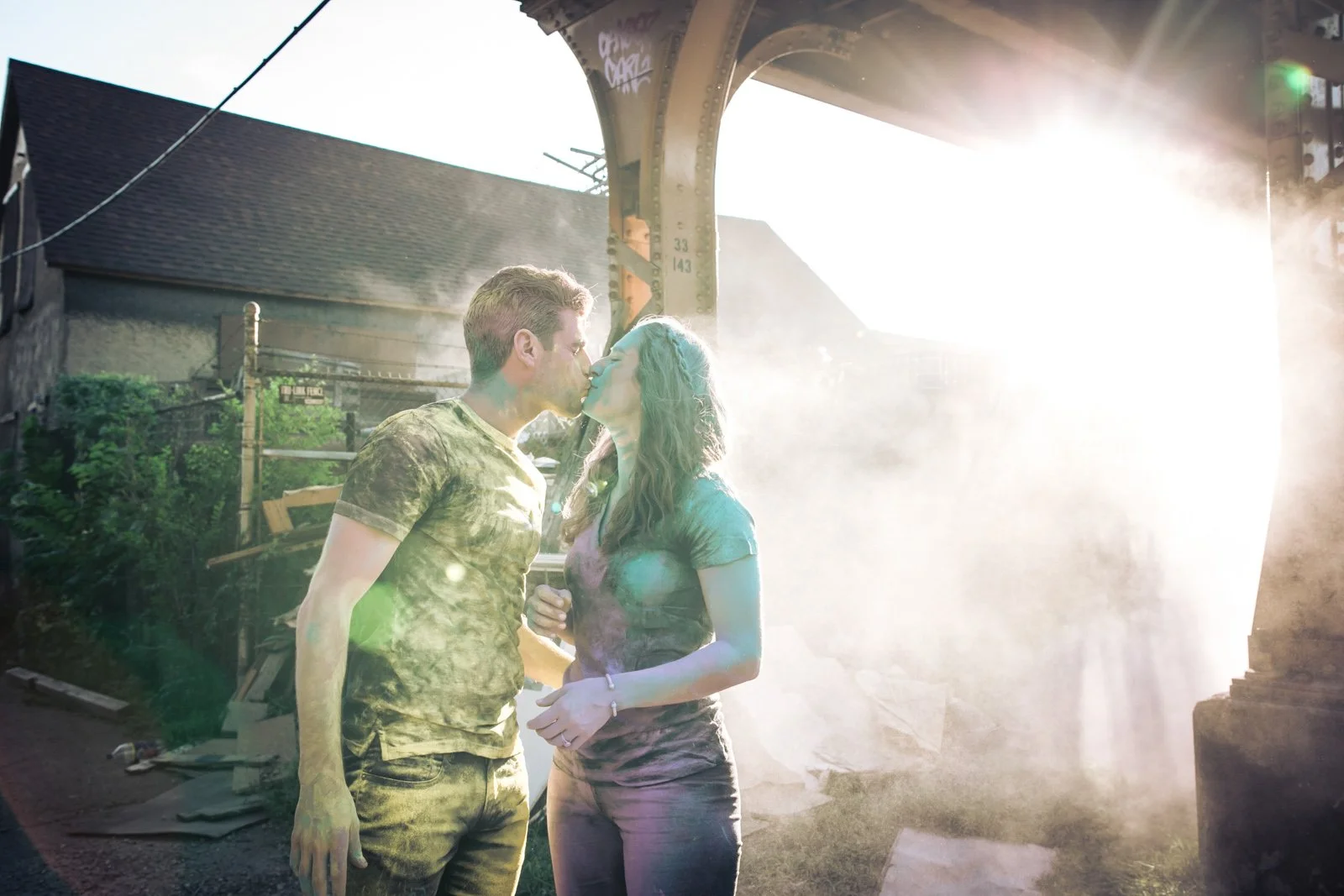 holi powder engagement photo session kiss under el track Chicago wedding photographer near me