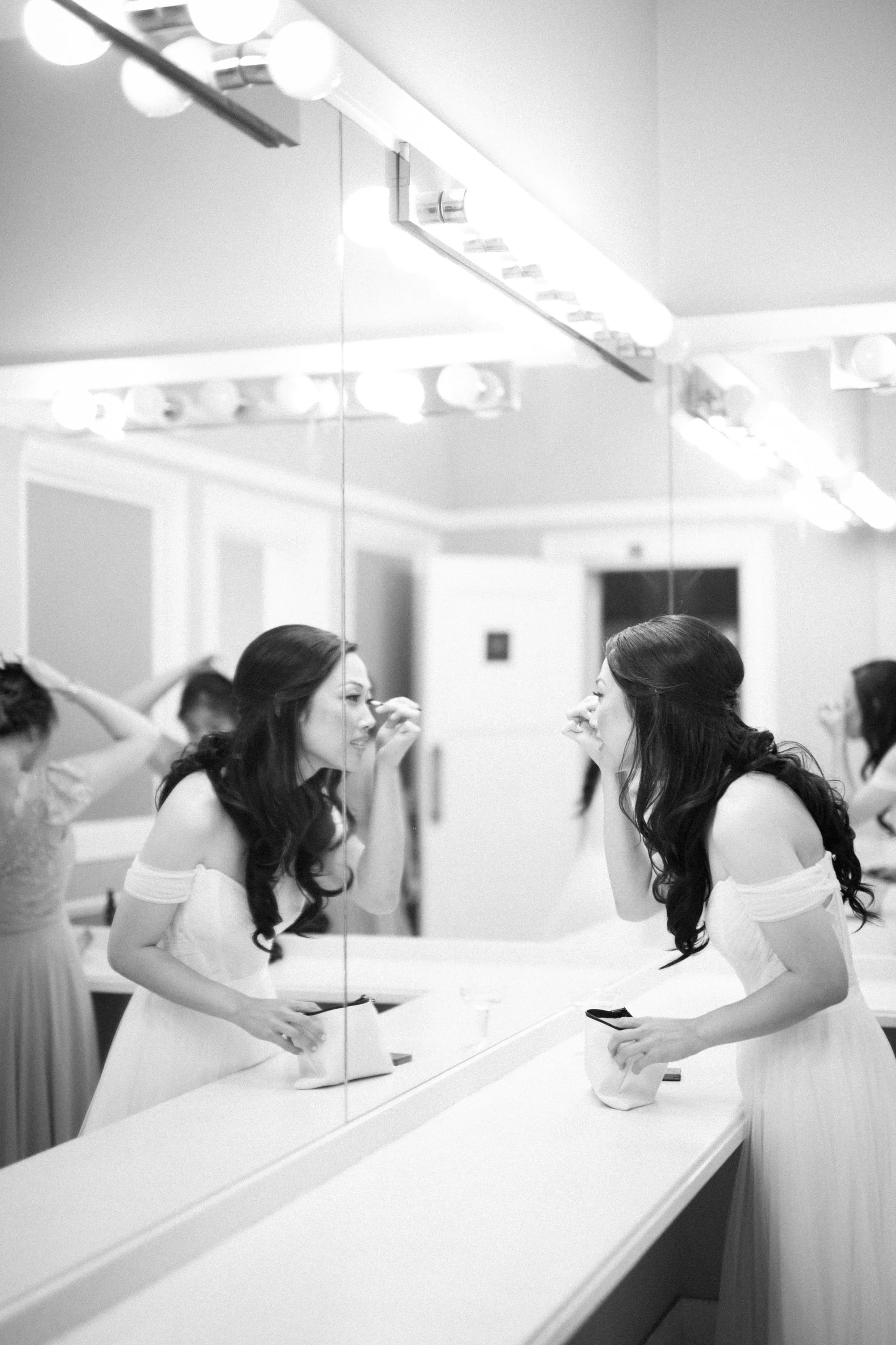 bride applying makeup looking in a mirror wedding photography