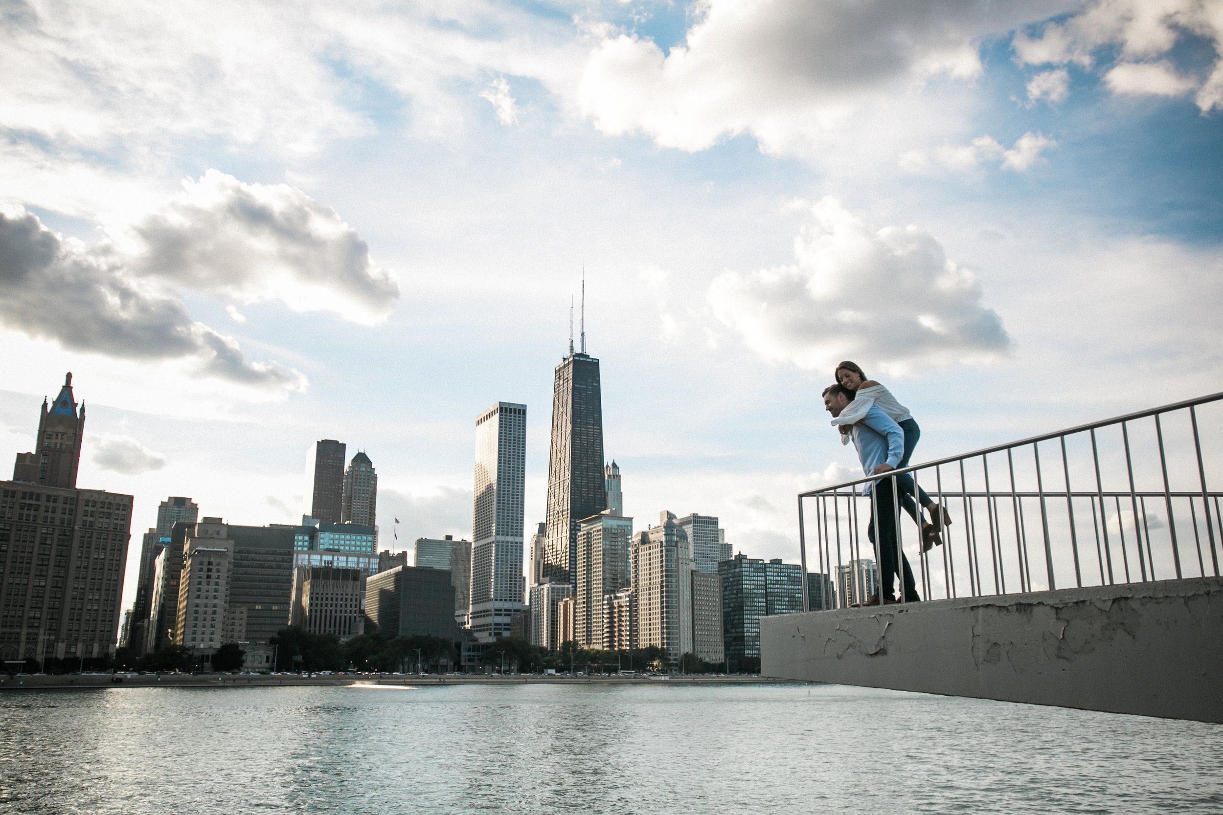 woman jumping on man's back near lake michigan in chicago
