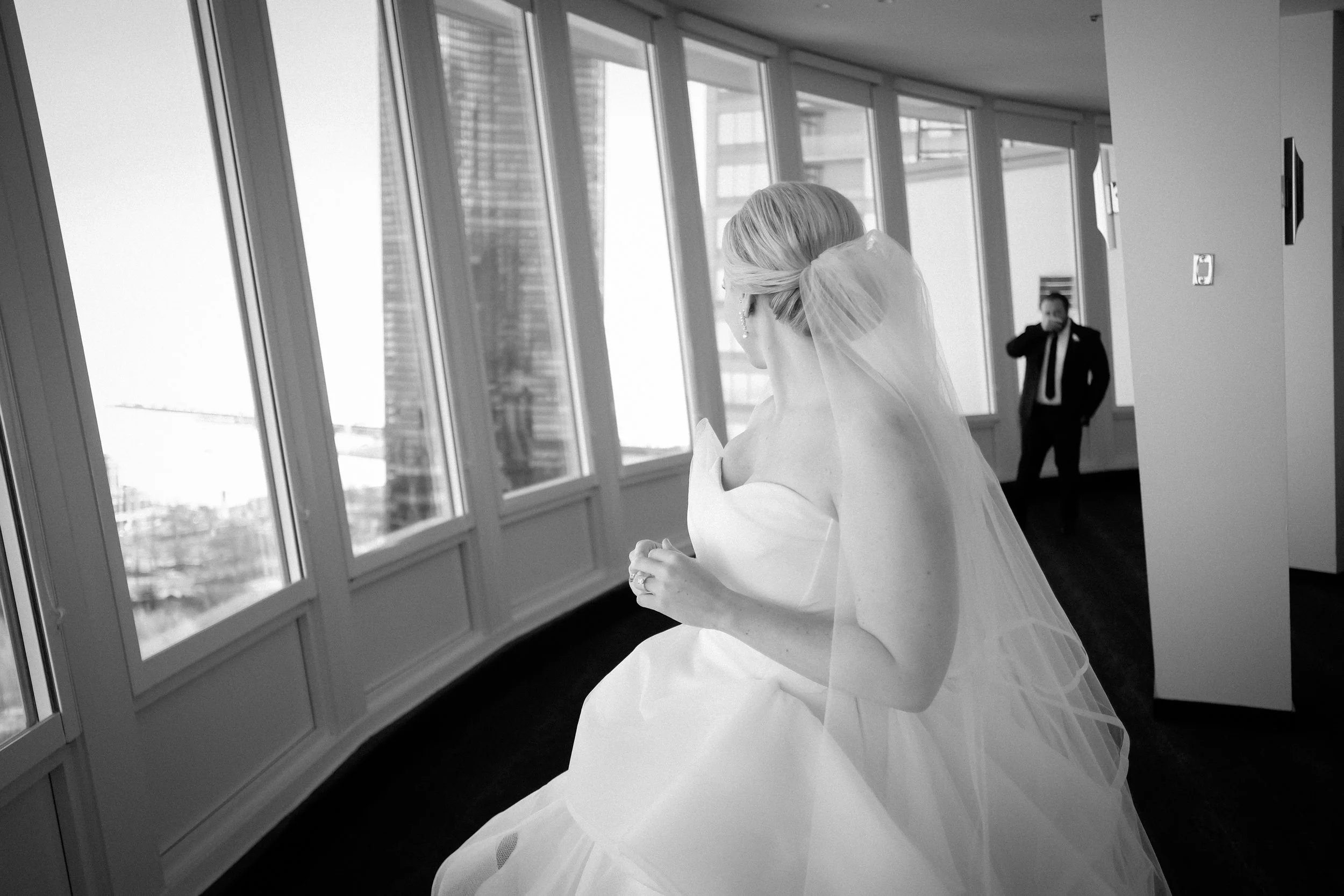 bride waiting for first look with groom looking out windows average price for wedding photographer