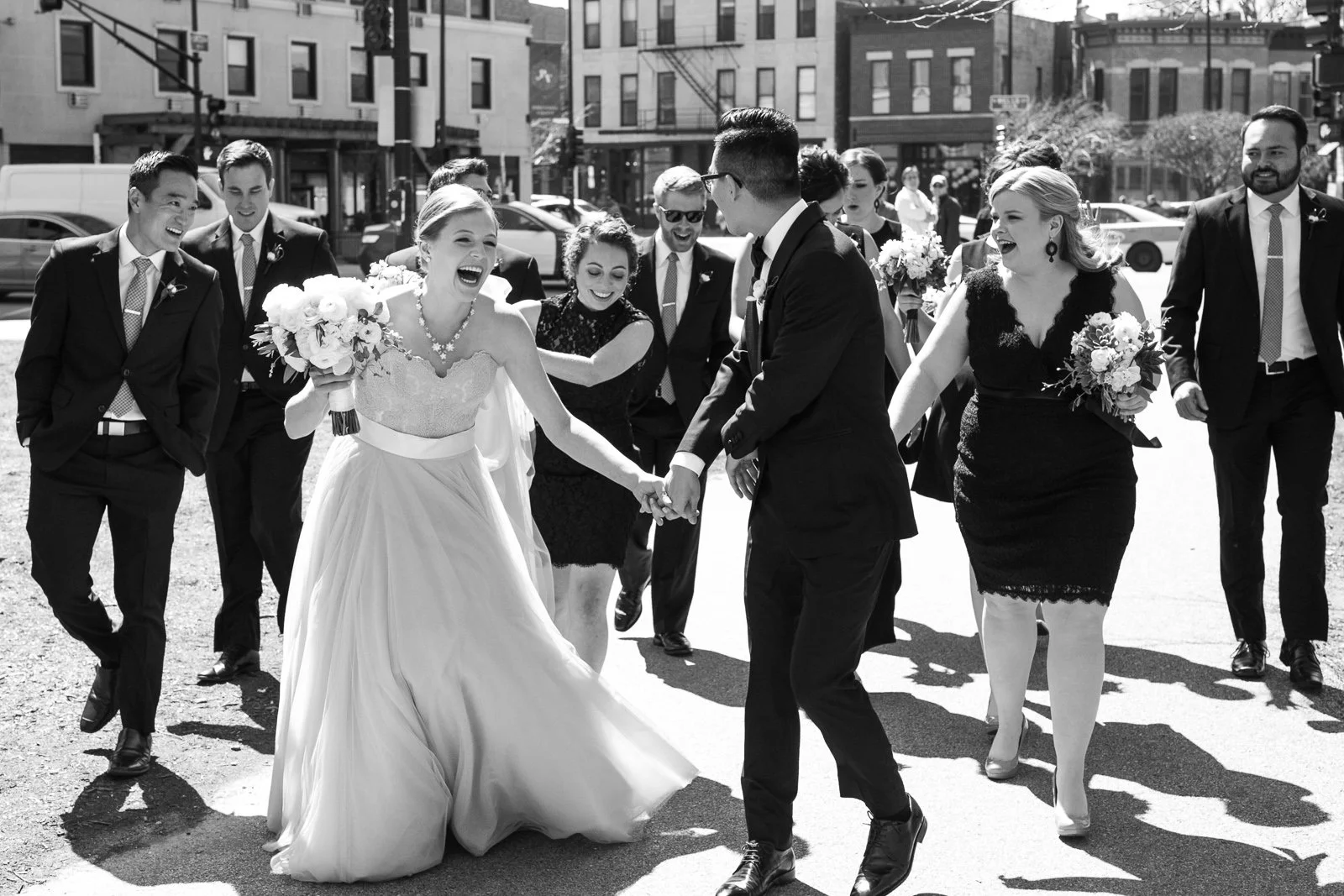 bride and groom laughing walking with bridal party wedding photography