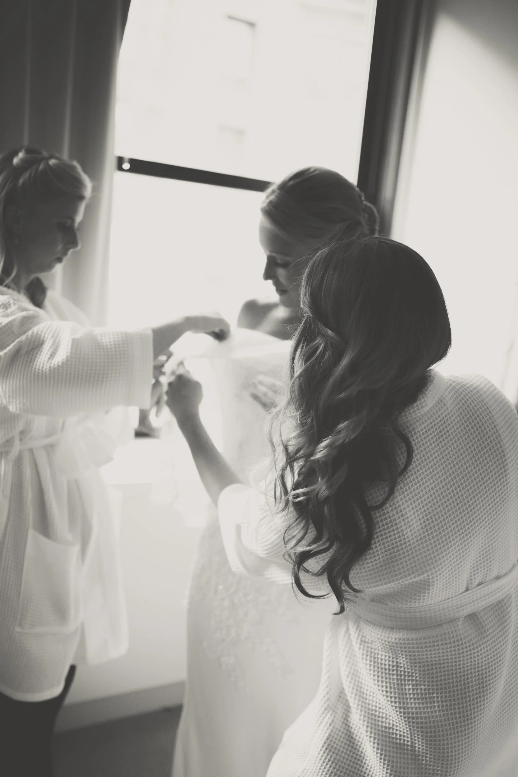 bride getting dressed near a window Chicago wedding photography