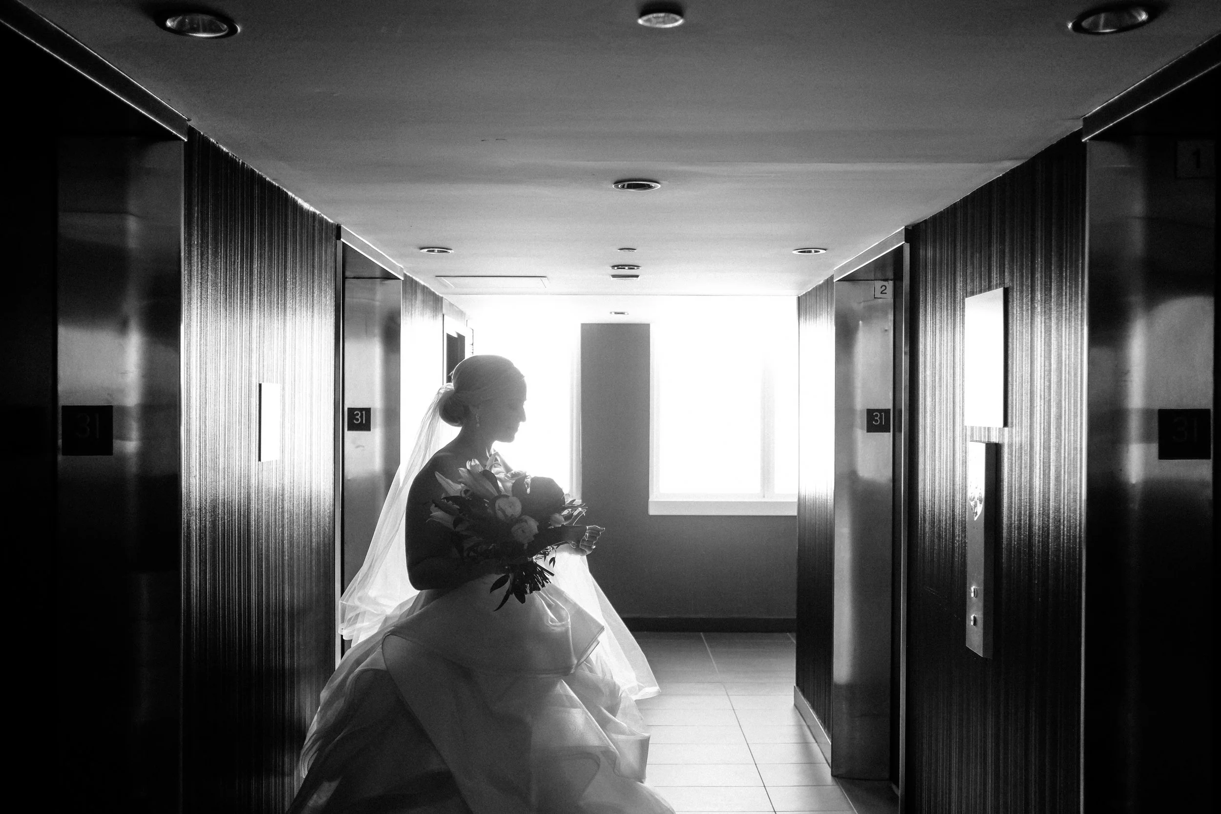 bride waiting for elevator to open with flowers average price for wedding photographer