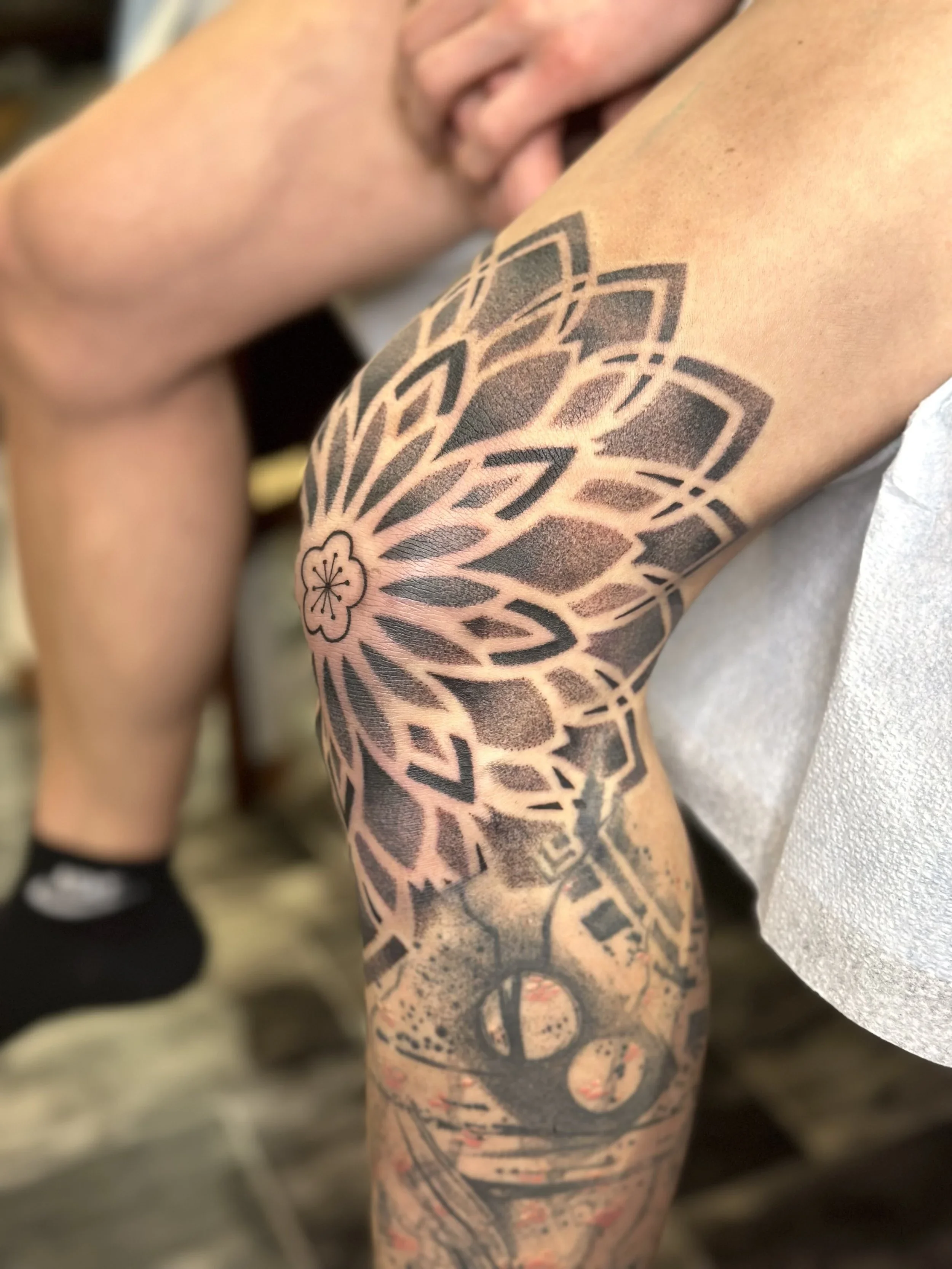 Close-up of a person's arm with a large, black geometric tattoo design.