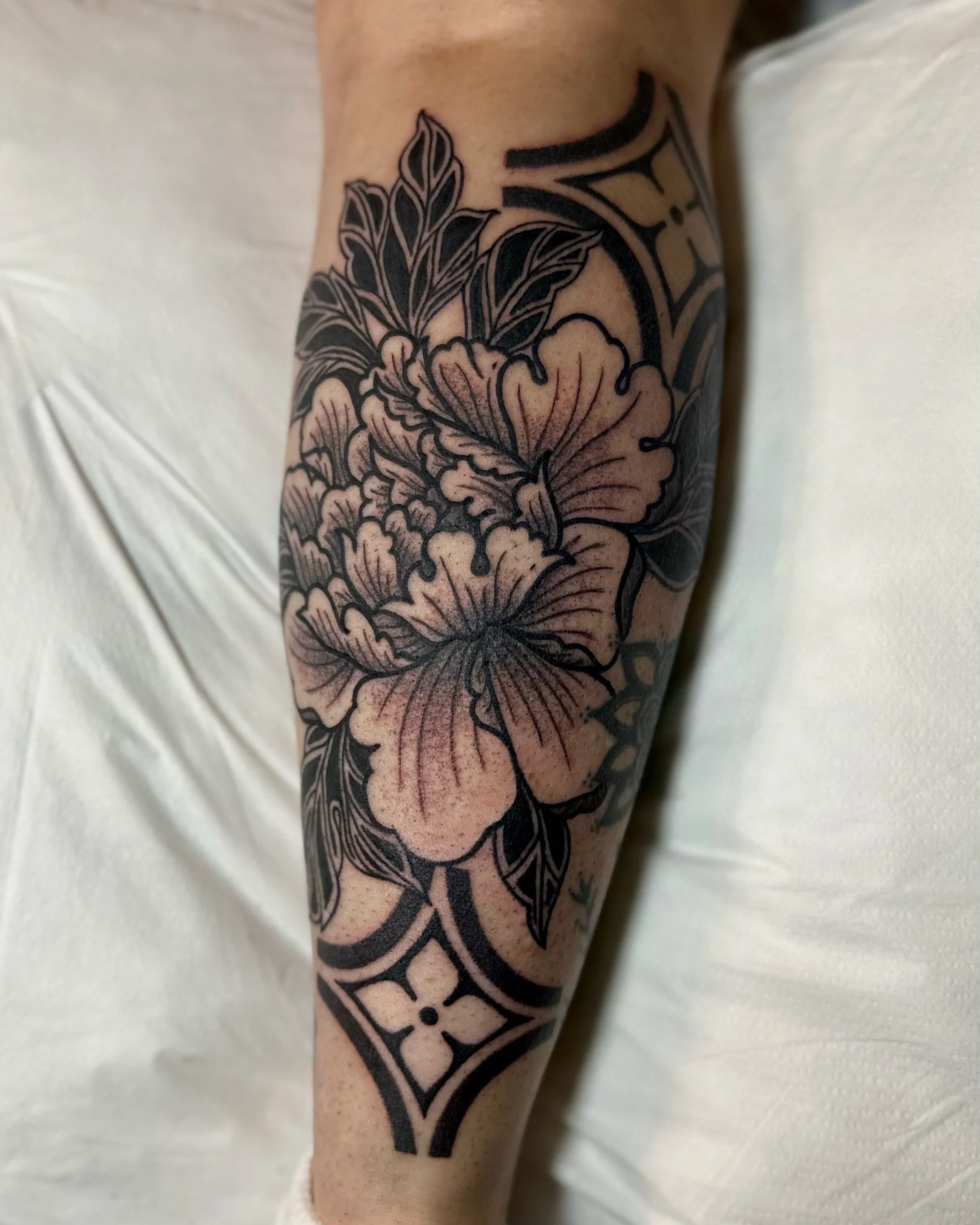 Close-up of a person's arm with a black floral tattoo.