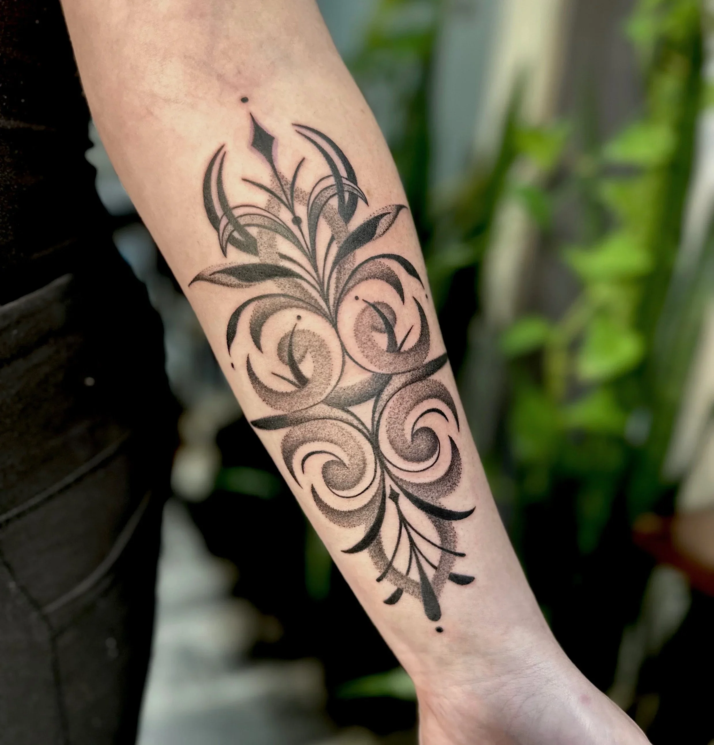 Tattoo of a stylized butterfly with black outlines and intricate details on a person's forearm.