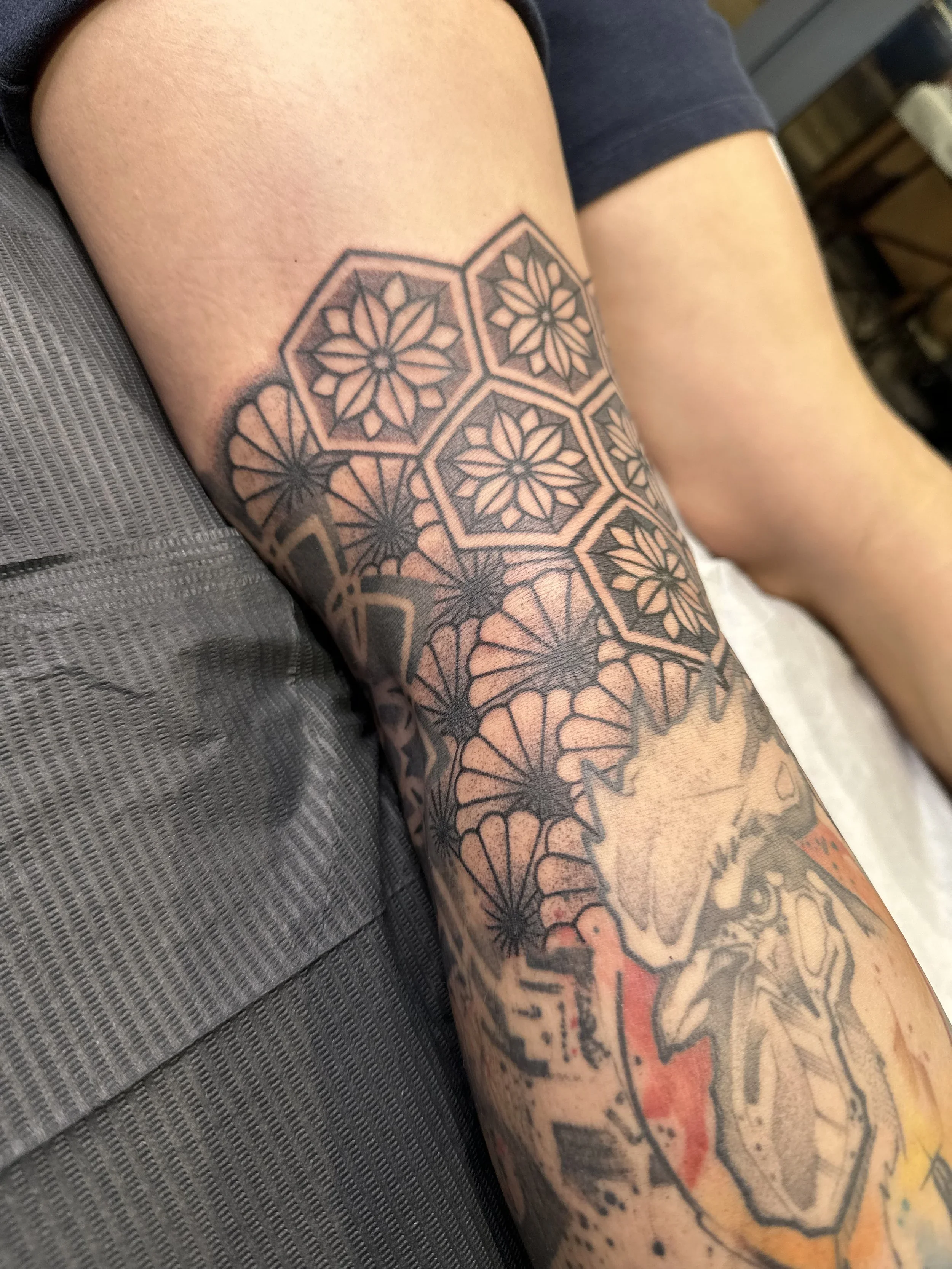 A tattoo of geometric floral patterns on a person's forearm.