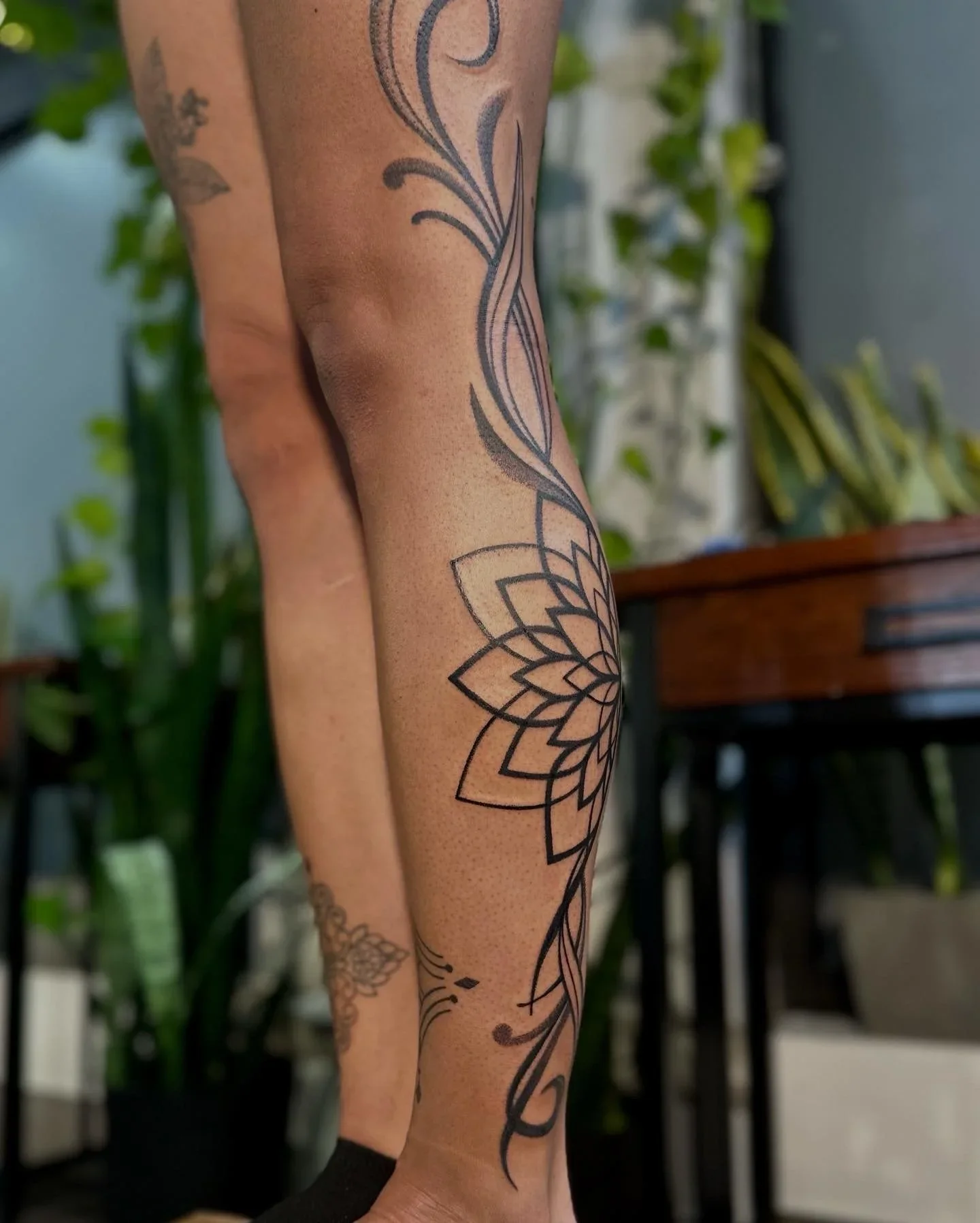 Arm with a large black outline floral tattoo design.