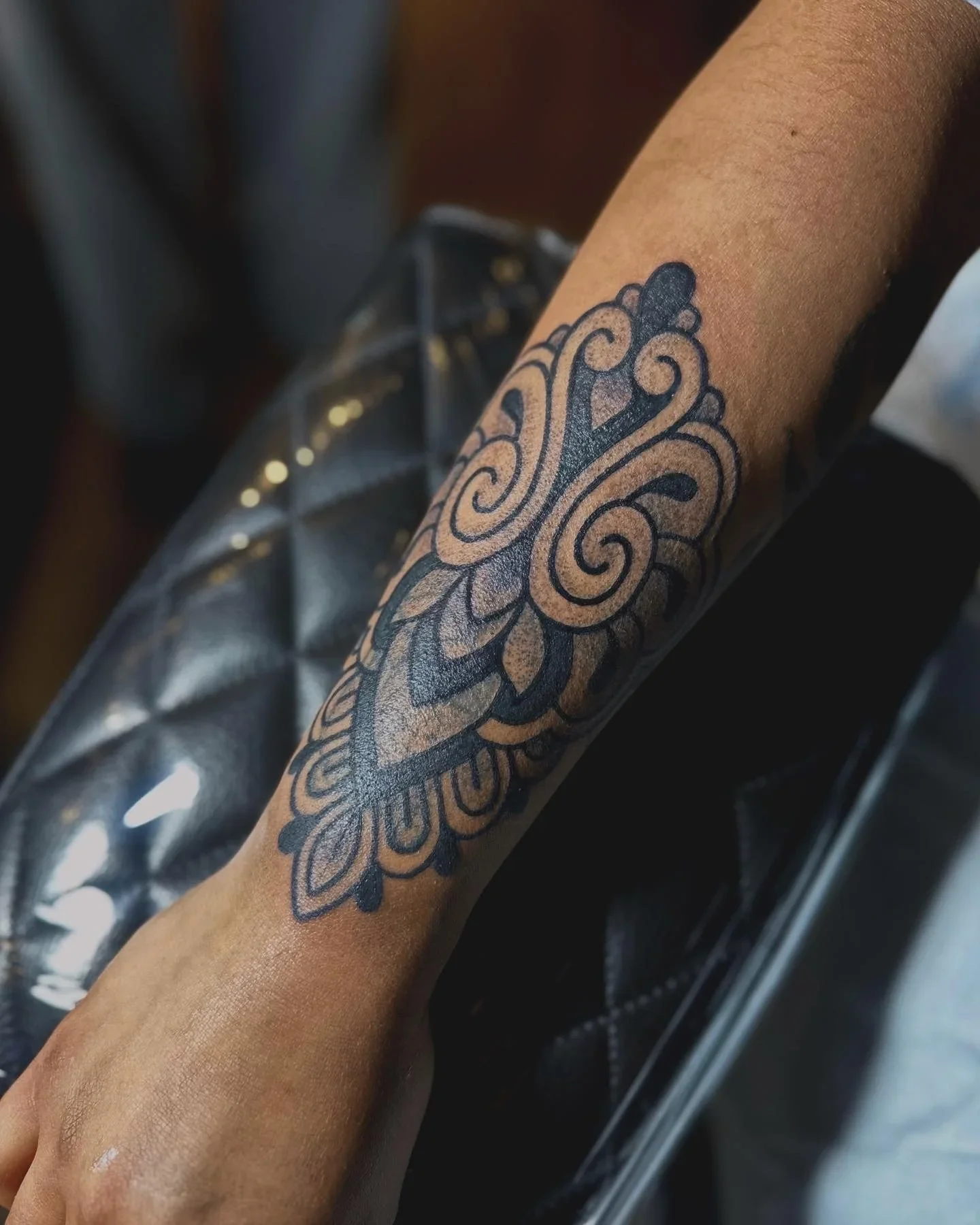 Tattoo of a decorative floral design on a person's forearm.