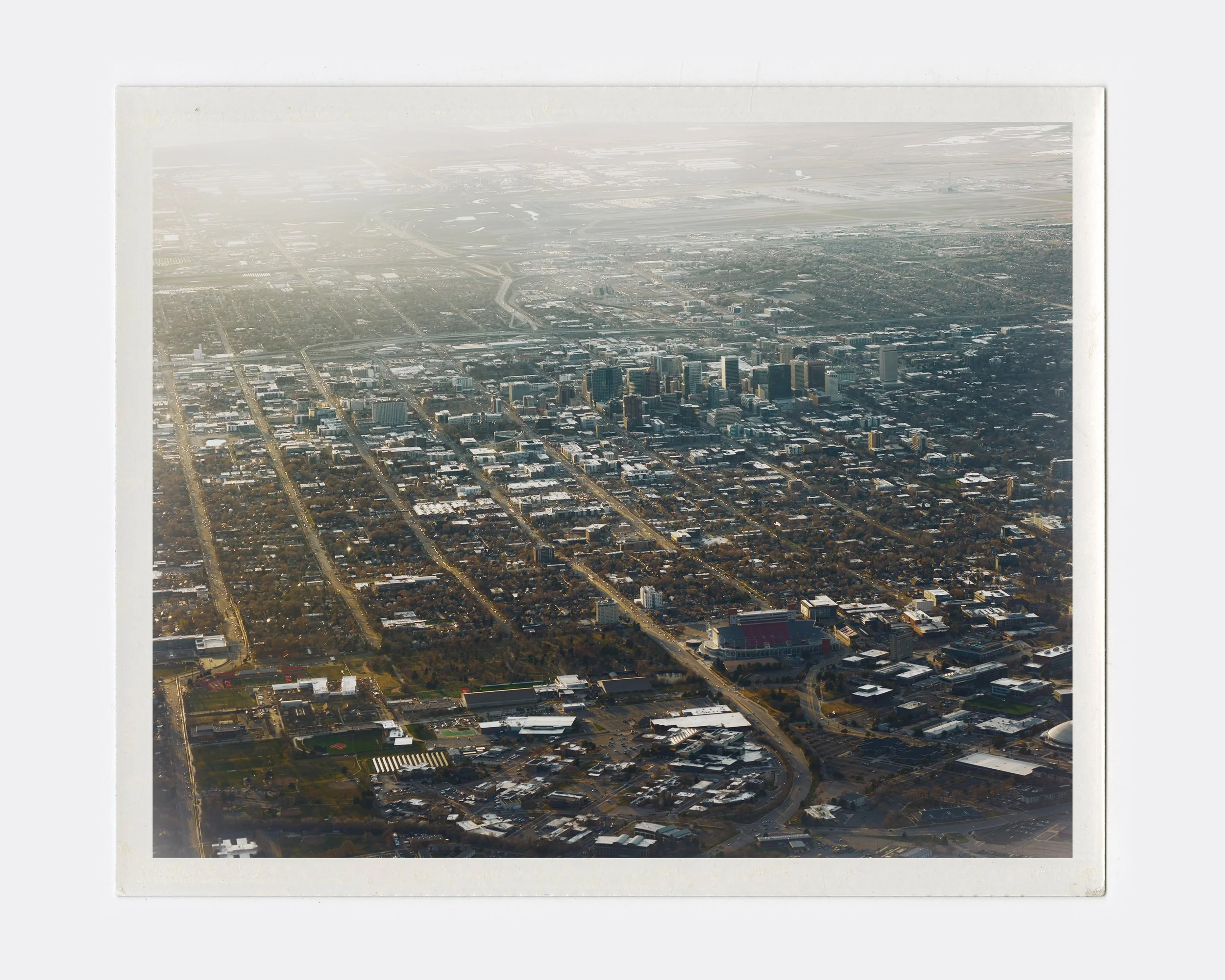 Aerial view of a cityscape showing a downtown area with tall buildings, surrounded by a grid of streets and residential neighborhoods.
