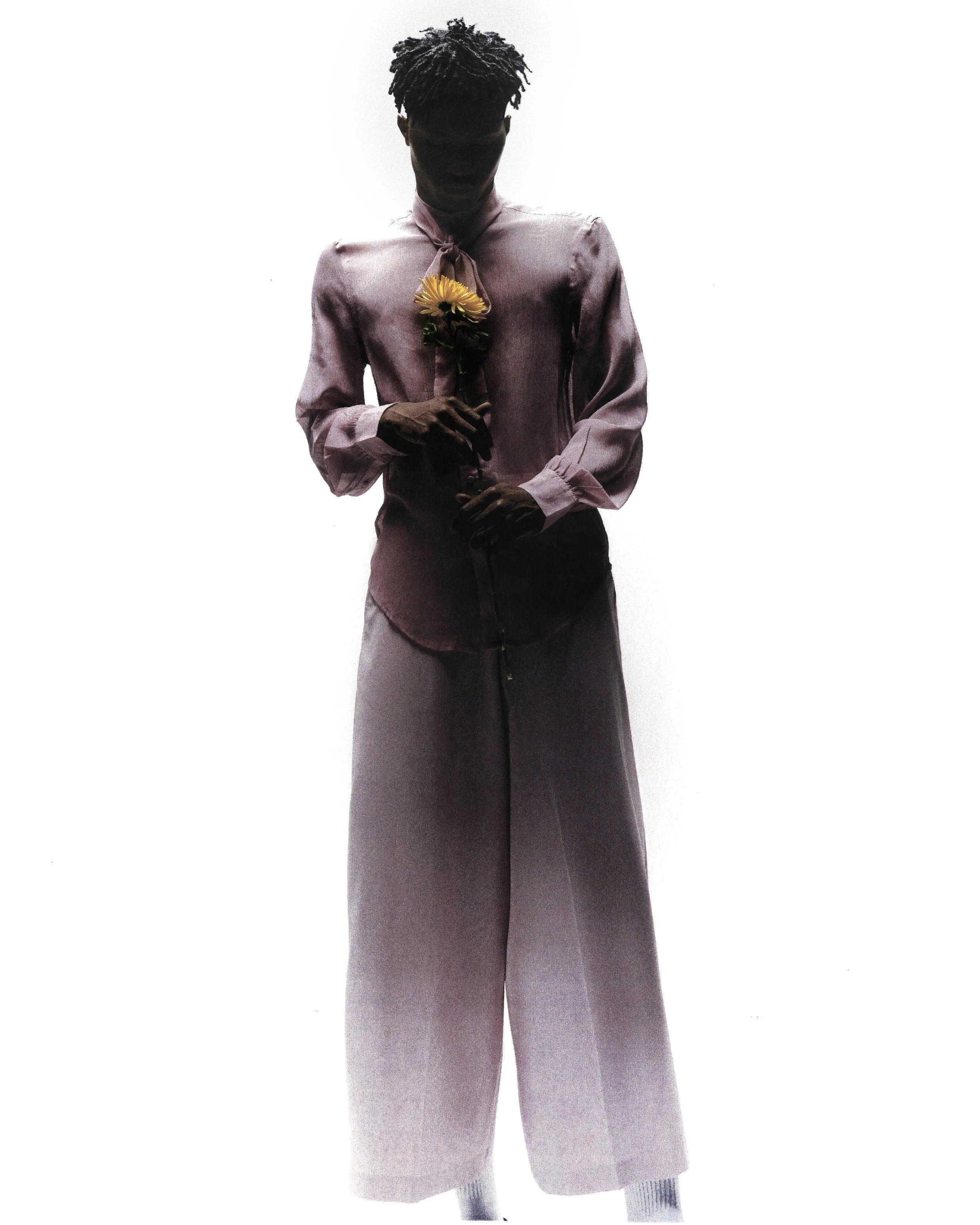 Silhouette of a person with curly hair wearing a long skirt and a buttoned-up blouse, holding a flower against a plain white background.