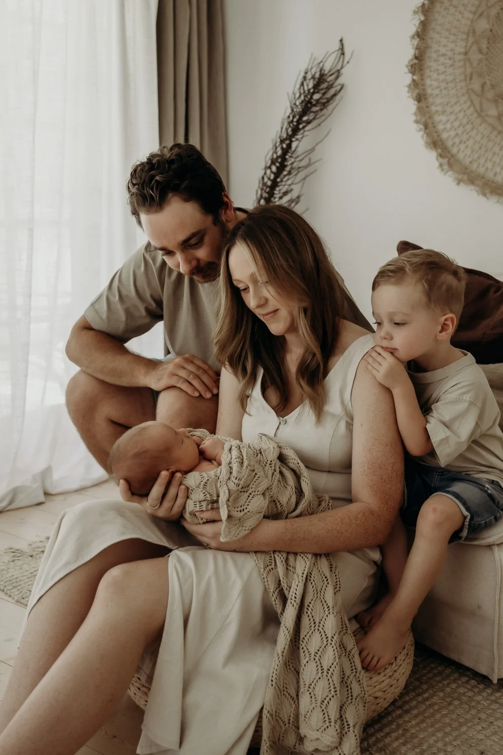 mum holding baby and dad and big brother looking over mums shoulder