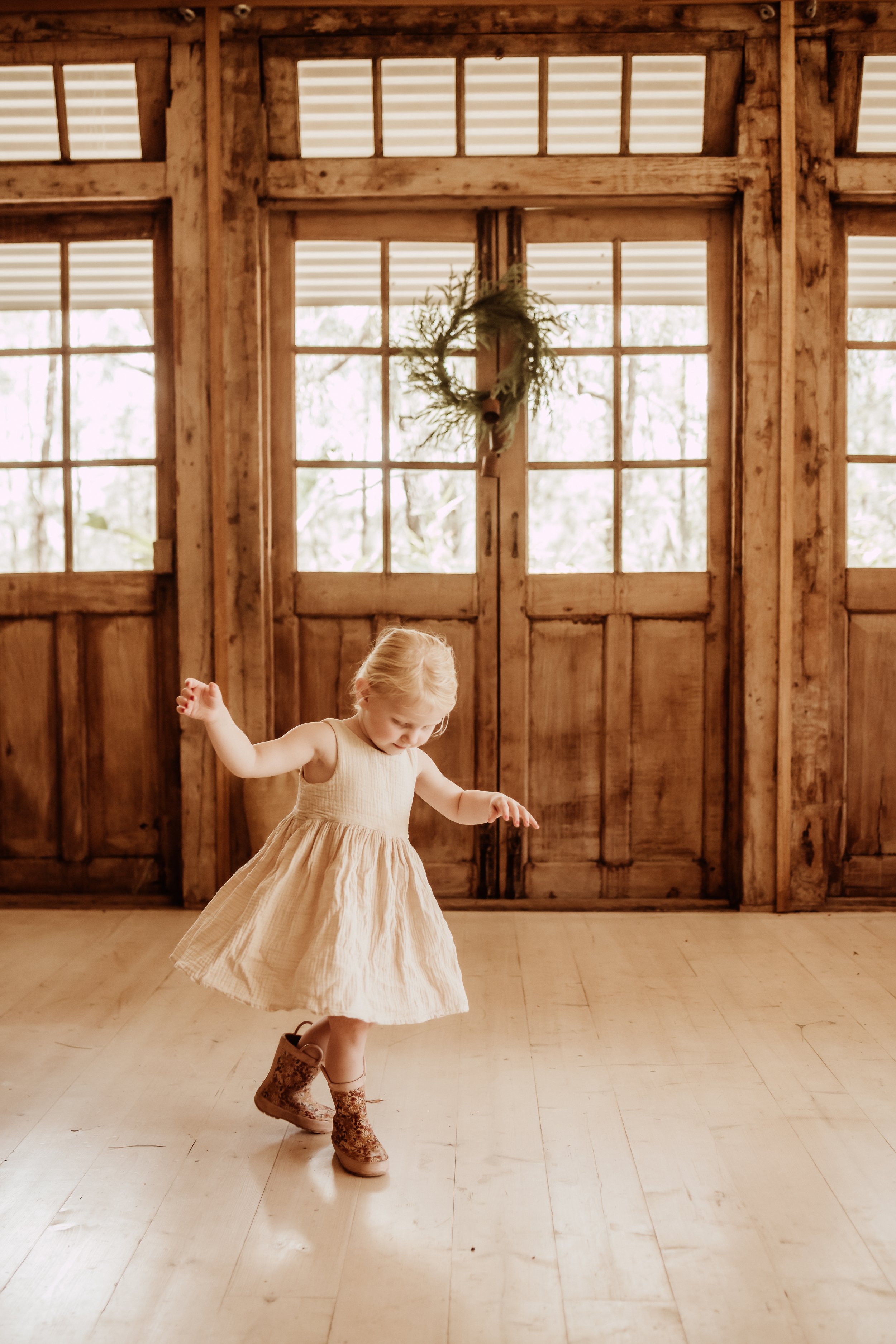 little girl dancing in front of christmas wreath