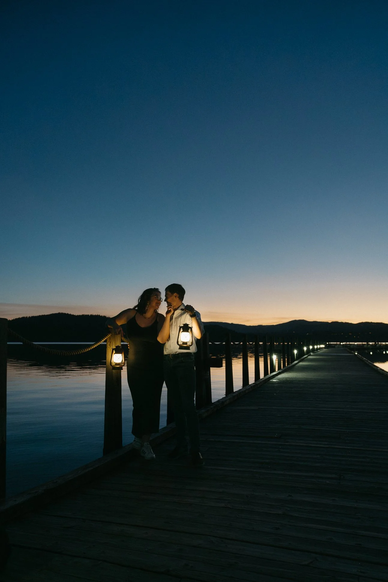 Couple holding lanterns while on a floating boardwalk in Coeur d'Alene, Idaho