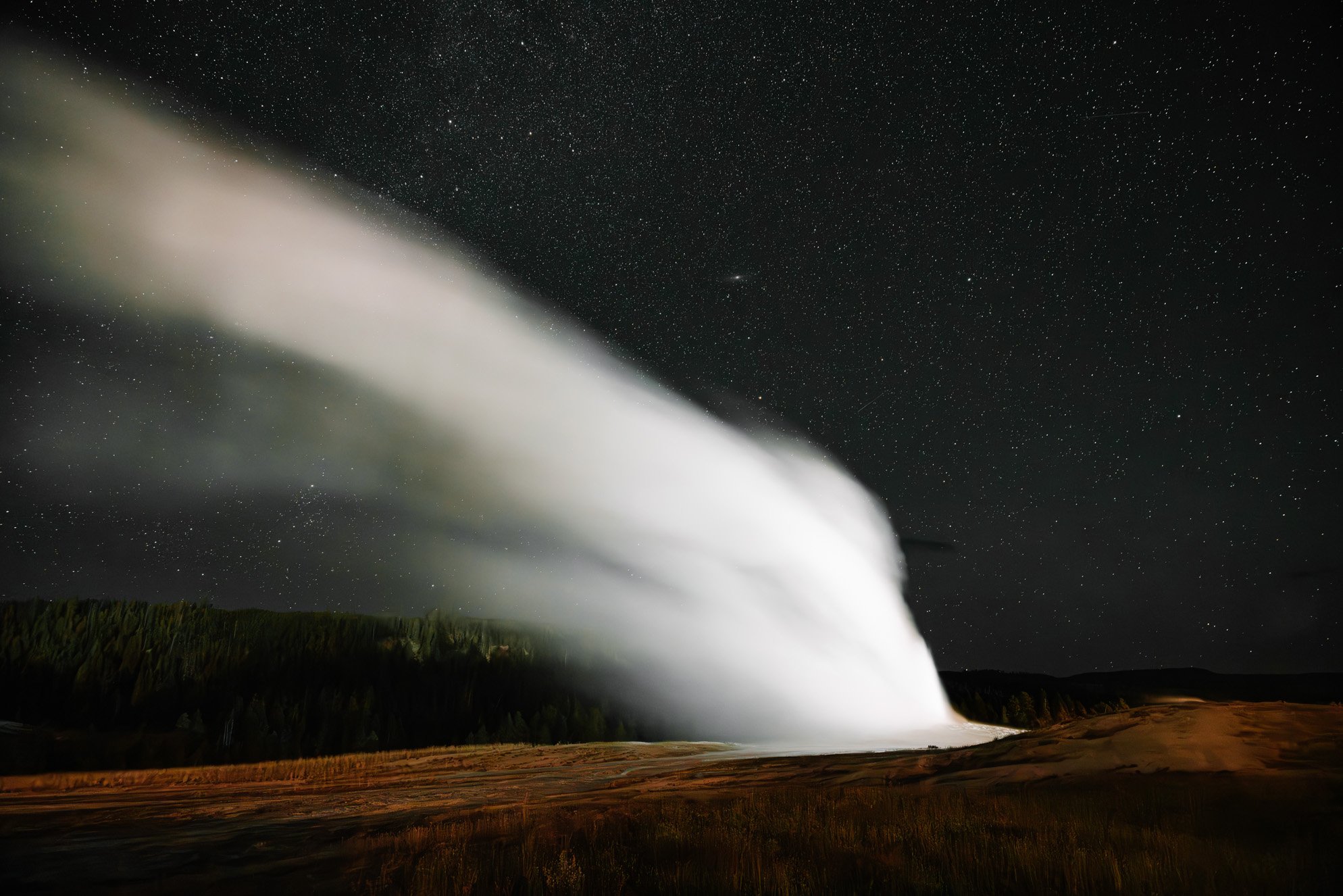 Old Faithful Geyser erupting under a star filled sky in Yellowstone National Park