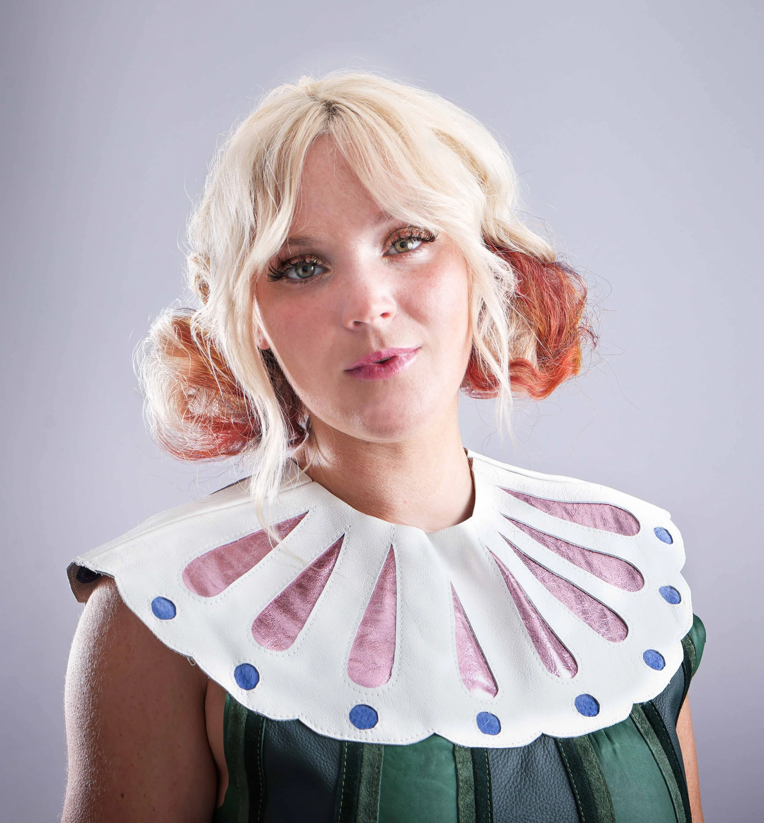 Portrait of a woman with blond hair in side buns wearing a green collared dress