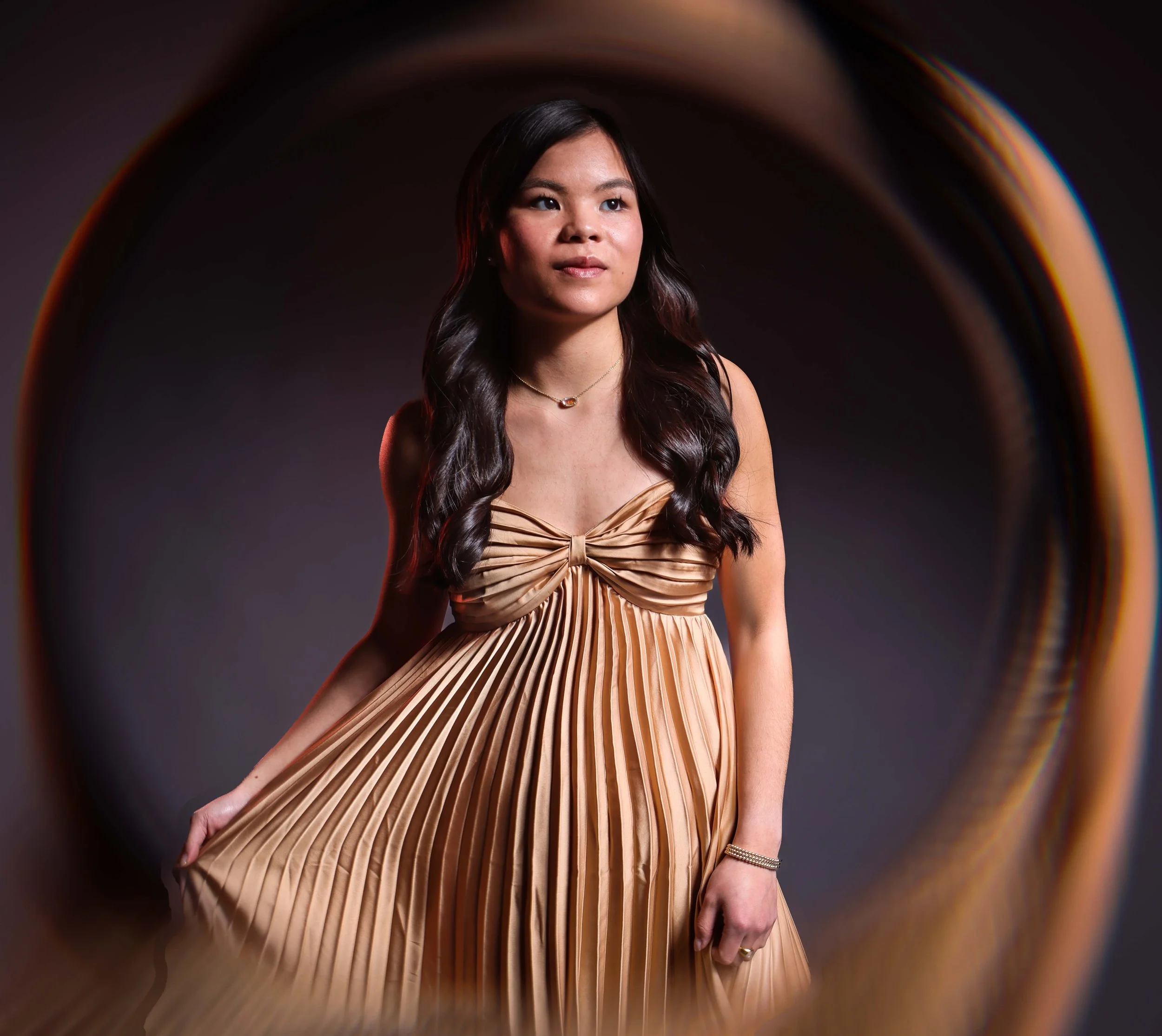 Creative portrait of an Asian American woman wearing a gold dress. 