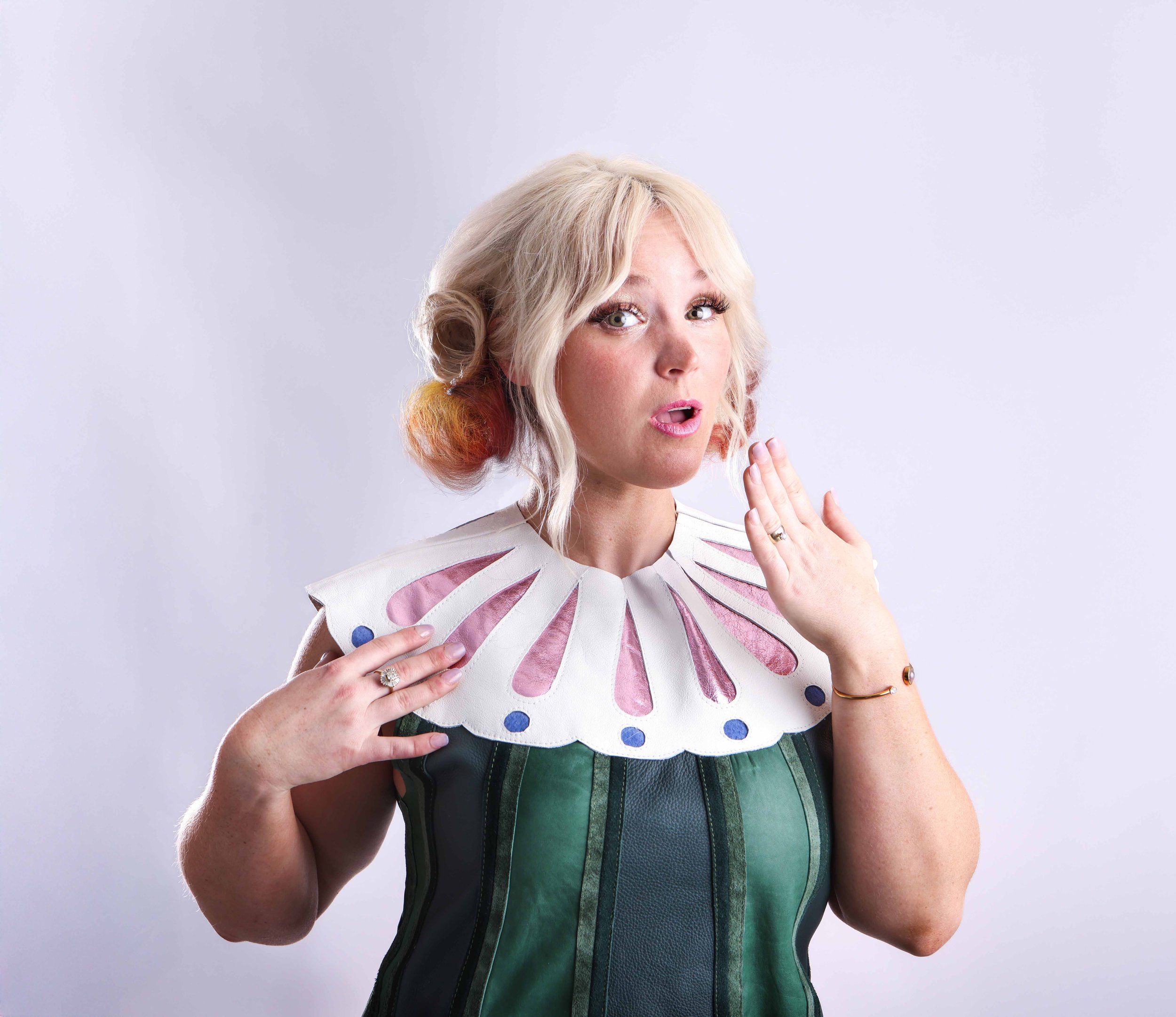 Portrait of a blond woman wearing a green collared dress with a cute expression