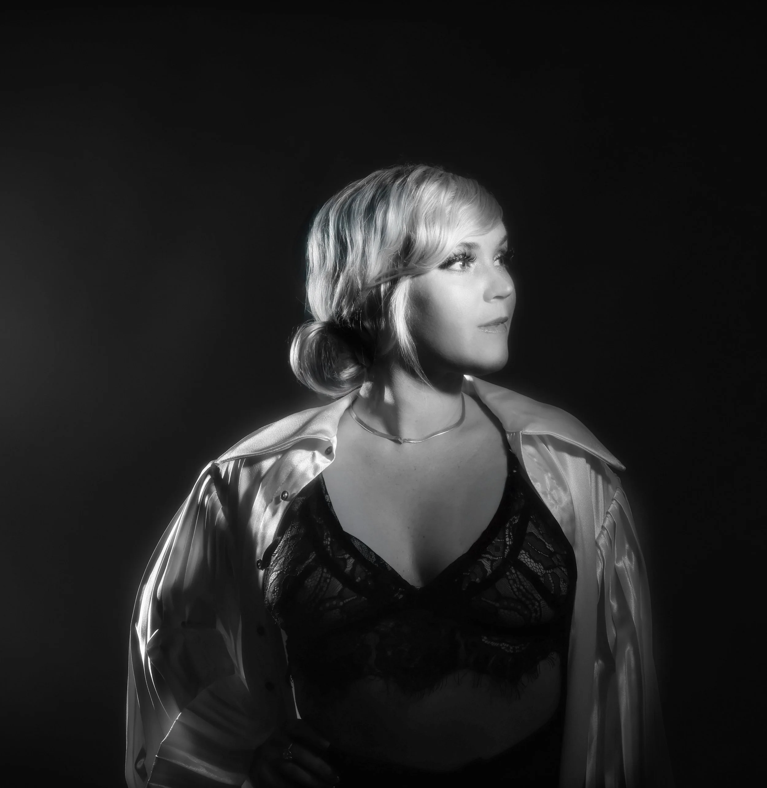 Black and white high contrast portrait of a woman with blond hair wearing a black bralette