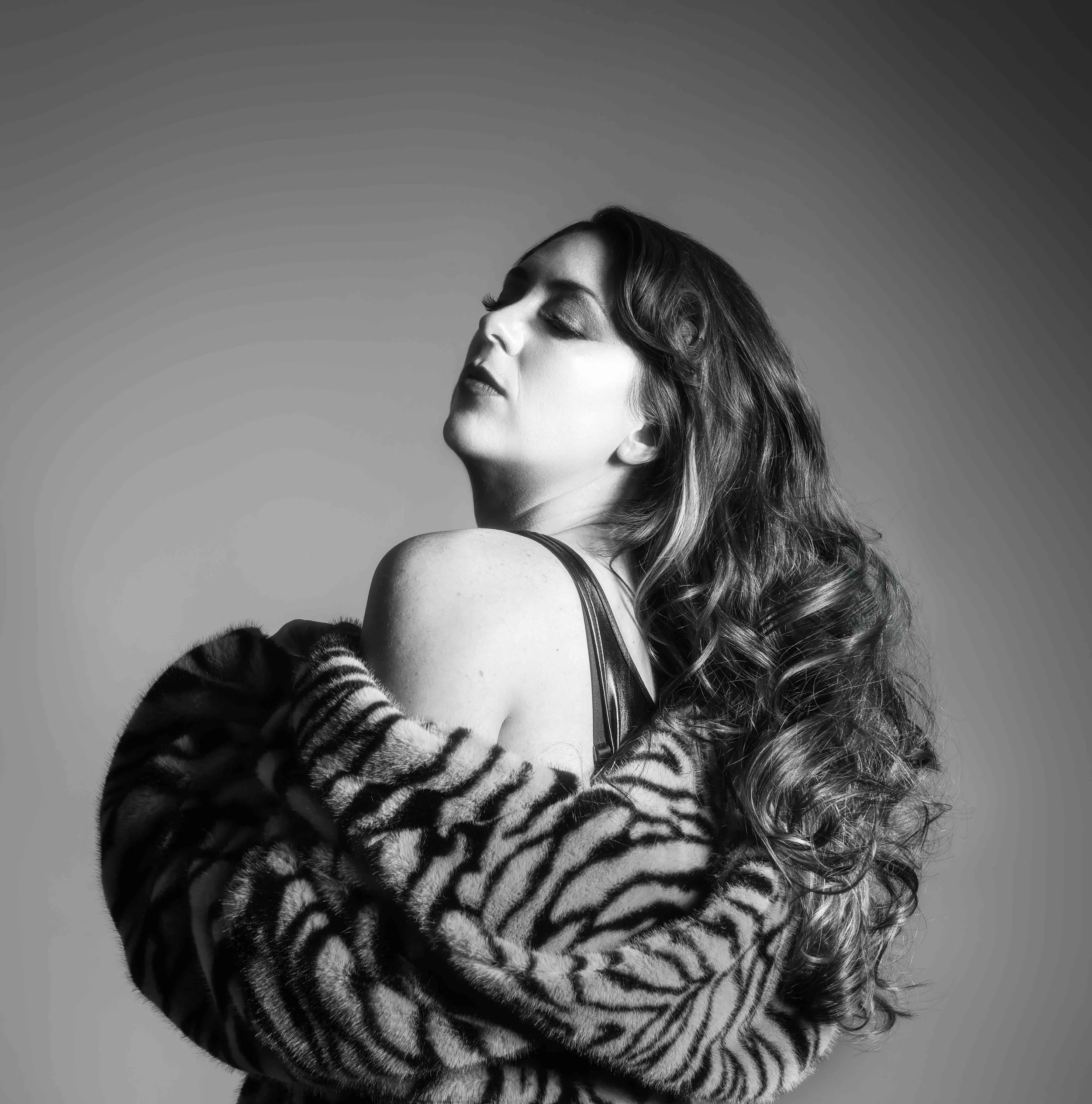 Regenerate alt text copyIconcrossIconBlue Black and white photo of a woman in a fur coat, eyes closed—perfect inspiration for portrait photographers near me.