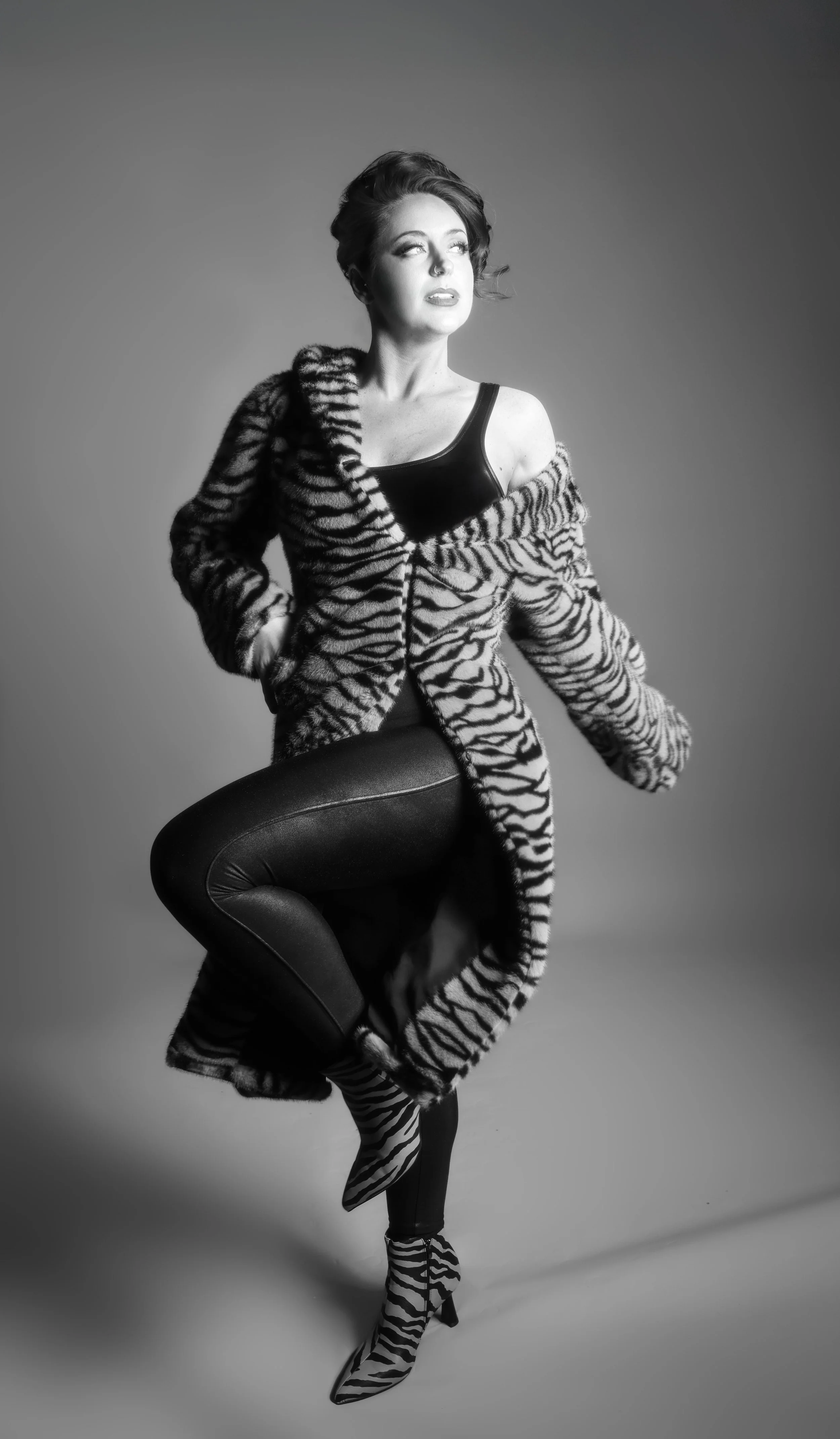 Regenerate alt text copyIconcrossIconBlue Woman in zebra print coat poses on one leg in this black and white photo. Find portrait photographers near me for similar shots.