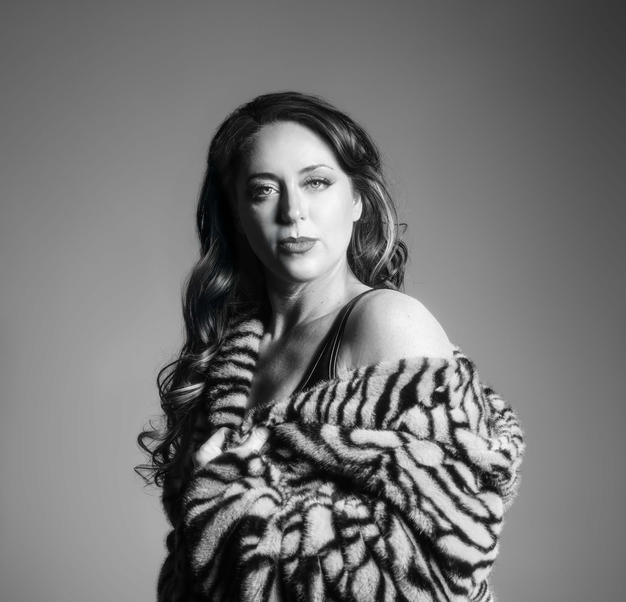 Regenerate alt text copyIconcrossIconBlue Black and white portrait of a woman in a patterned fur coat, captured in the style of top portrait photographers near me.