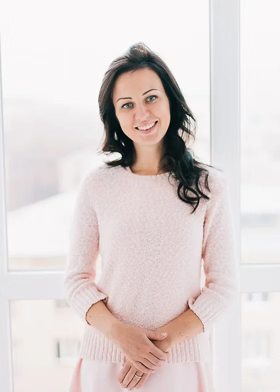 woman with brown hair in pink soft outfit holding hands together in a professional photograph