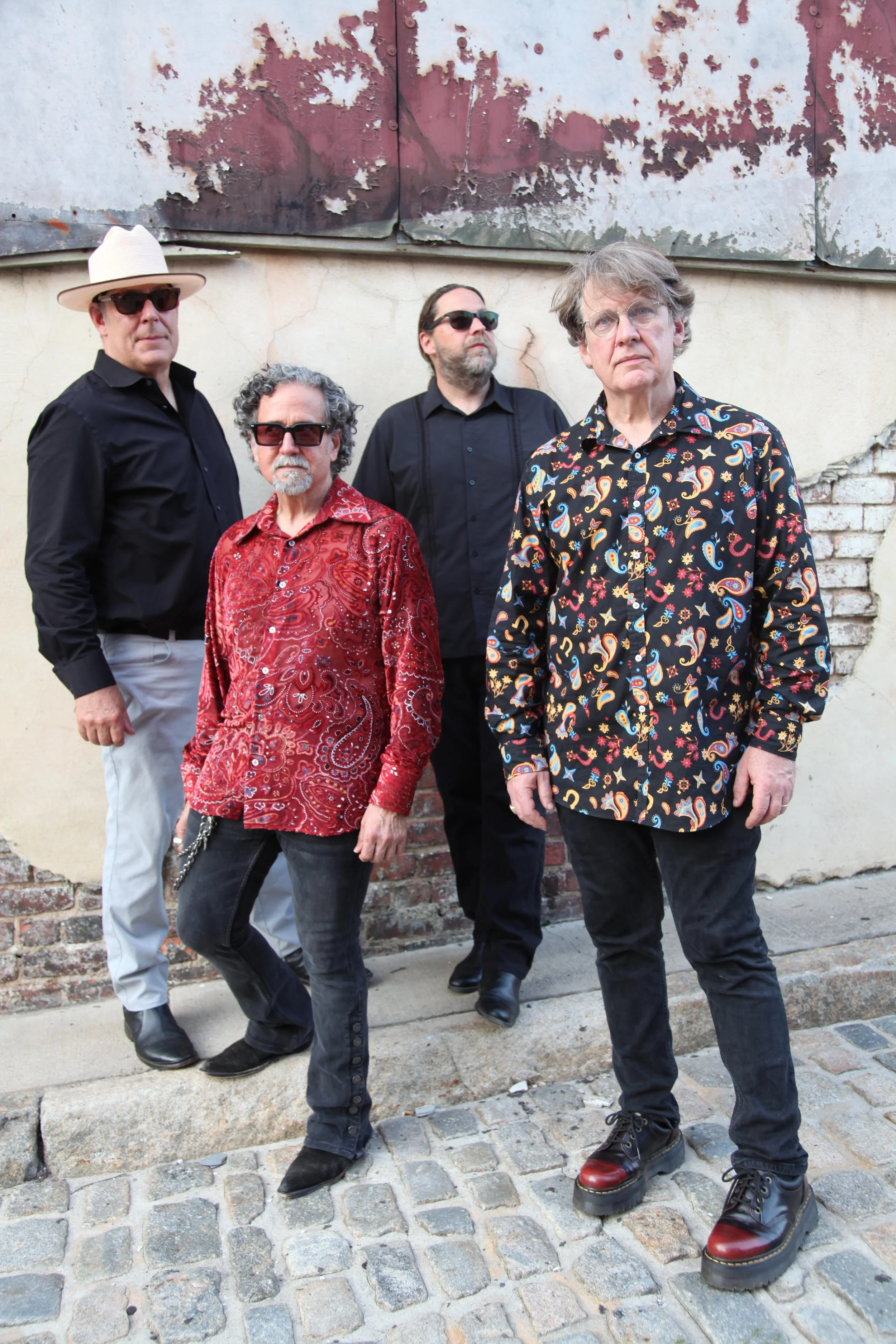 Four men standing close together, wearing casual clothing and smiling at the camera.